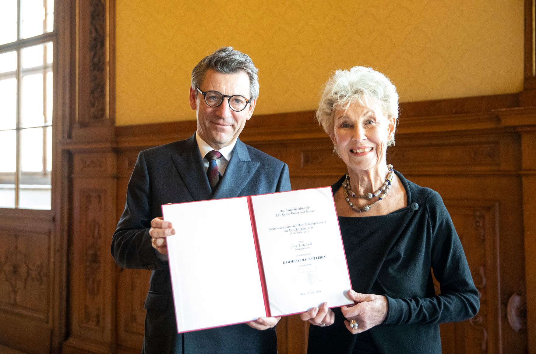 Am 22. März 2019 überreichte Sektionschef Jürgen Meindl (l.) die Urkunde, mit der Lotte Ledl (r.) der Berufstitel Kammerschauspielerin verliehen wurde.