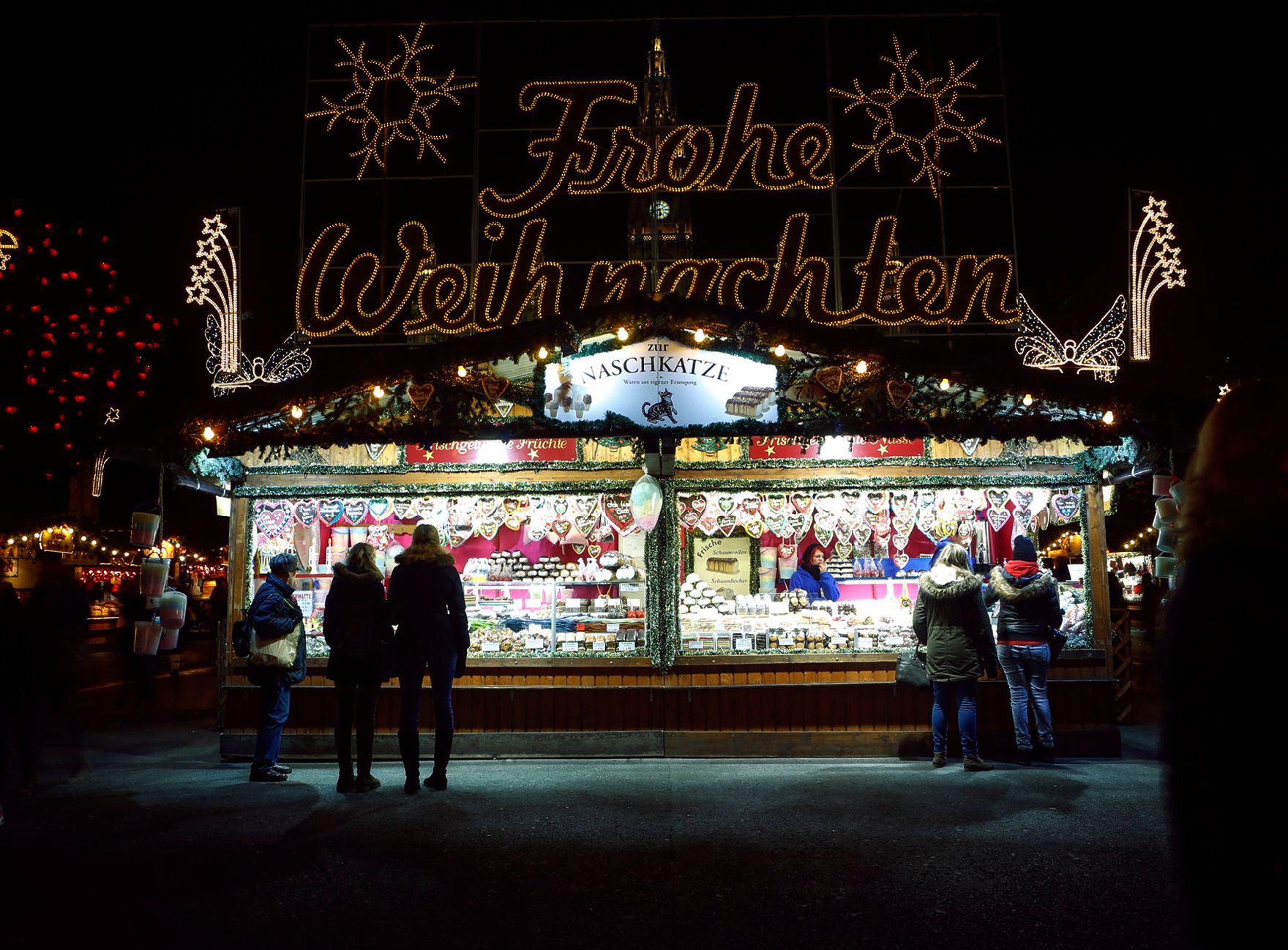 Der Christkindlmarkt am Rathausplatz bei Nacht. Schlagworte: Abend, Beleuchtung, Kugeln, Marktstand, Menschen, Sehenswürdigkeit, Stadtlandschaften, Weihnachten