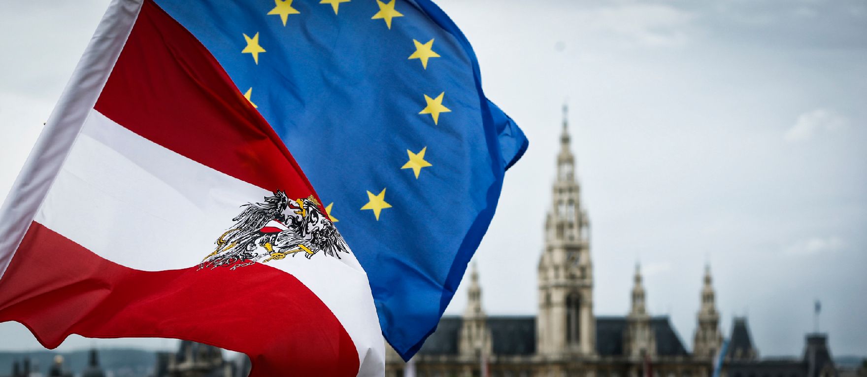 Die österreichische und europäische Fahne wehen im Wind. Im Hintergrund das Rathaus. Schlagworte: Bundesadler, Fahnen, Flaggen