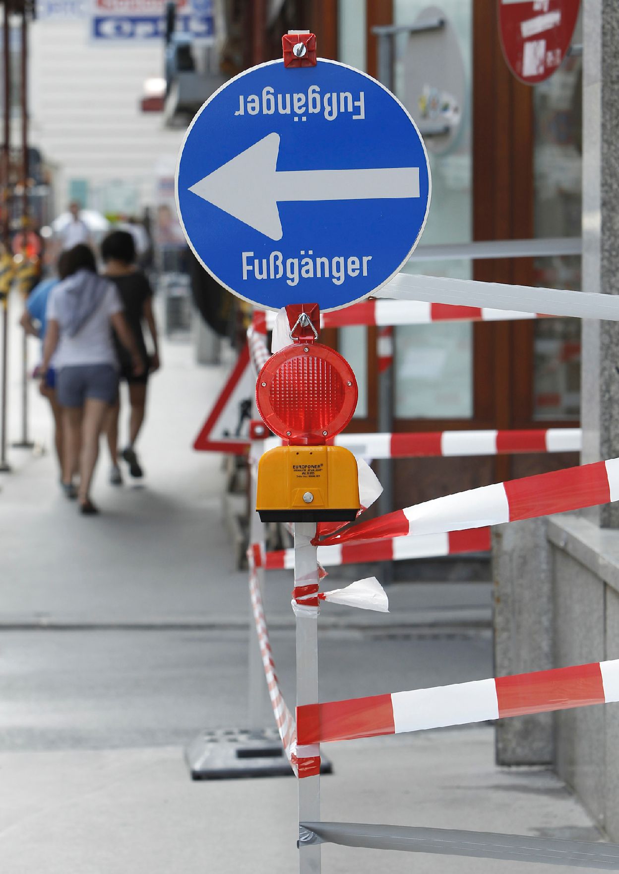 Verkehrsschild "Fußgänger" mit Richtungspfeil links, Absperrband und Warnleuchte. Schlagworte: Beschriftung, Verkehr, Verkehrsschild, Verkehrszeichen