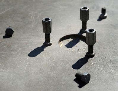 Schrauben werfen ihre Schatten auf einen metallischen Untergrund. Schlagworte: Mechanik, Metall, Mutter, Technik