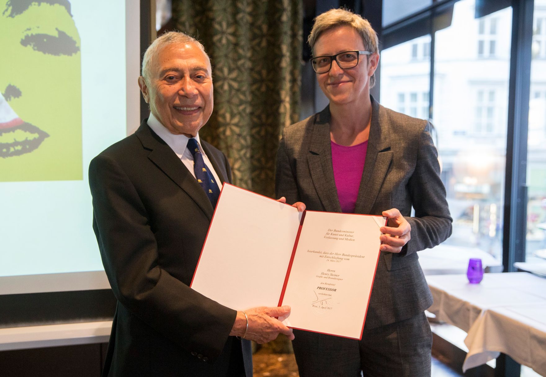 Am 3. Oktober 2017 &uuml;berreichte Theresia Niederm&uuml;ller (r.) die Urkunde, mit der Henry Steiner (l.) der Berufstitel Professor verliehen wurde.