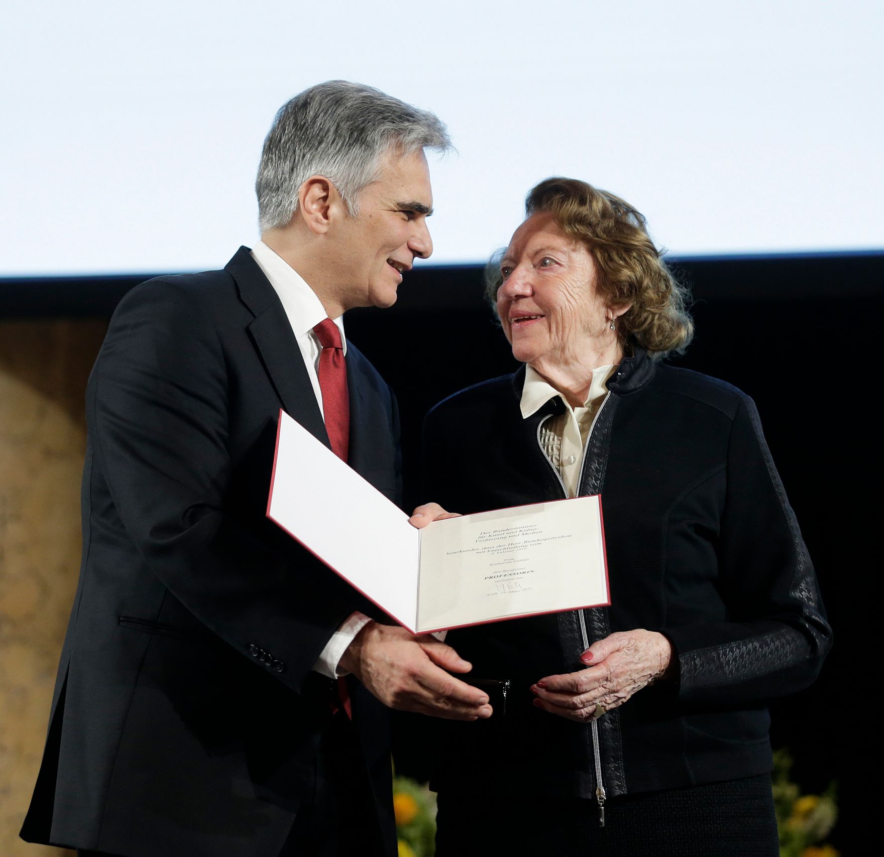 Am 8. April 2016 &uuml;berreichte Bundeskanzler Werner Faymann (l.) die Urkunde, mit der Katharina Sasso (r.) der Berufstitel Professorin verliehen wurde.