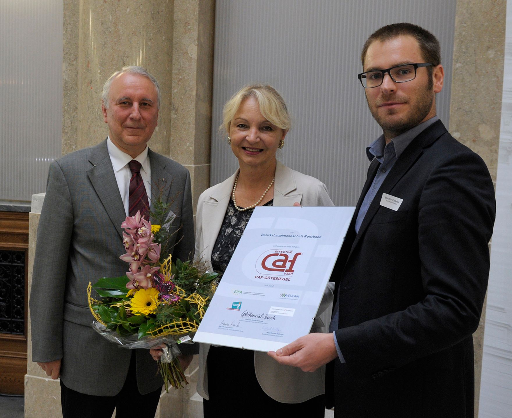 Am 17. Oktober 2013 &uuml;berreichte Andreas Buchta-Kadanka in Vertretung f&uuml;r Frauenministerin Gabriele Heinisch-Hosek das CAF-G&uuml;tesiegel an die Bezirkshauptmannschaft Rohrbach. Im Bild (r.) mit Bezirkshauptfrau Wilbirg Mitterlehner (m.) und dem Landesamtsdirektor von Ober&ouml;sterreich, Eduard Pesendorfer (l.).