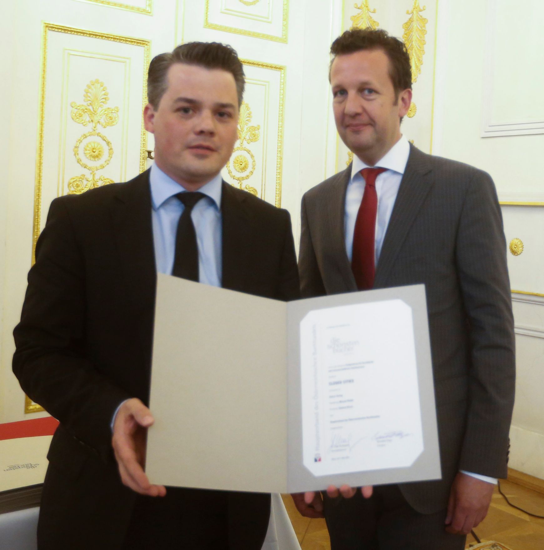 Am 7. Mai 2014 &uuml;berreichte der Pr&auml;sident des Hauptverbandes des &Ouml;sterreichischen Buchhandels Benedikt F&ouml;ger (r.) eine Ehrenurkunde an Tibor Valentin (l.) im Bundeskanzleramt.