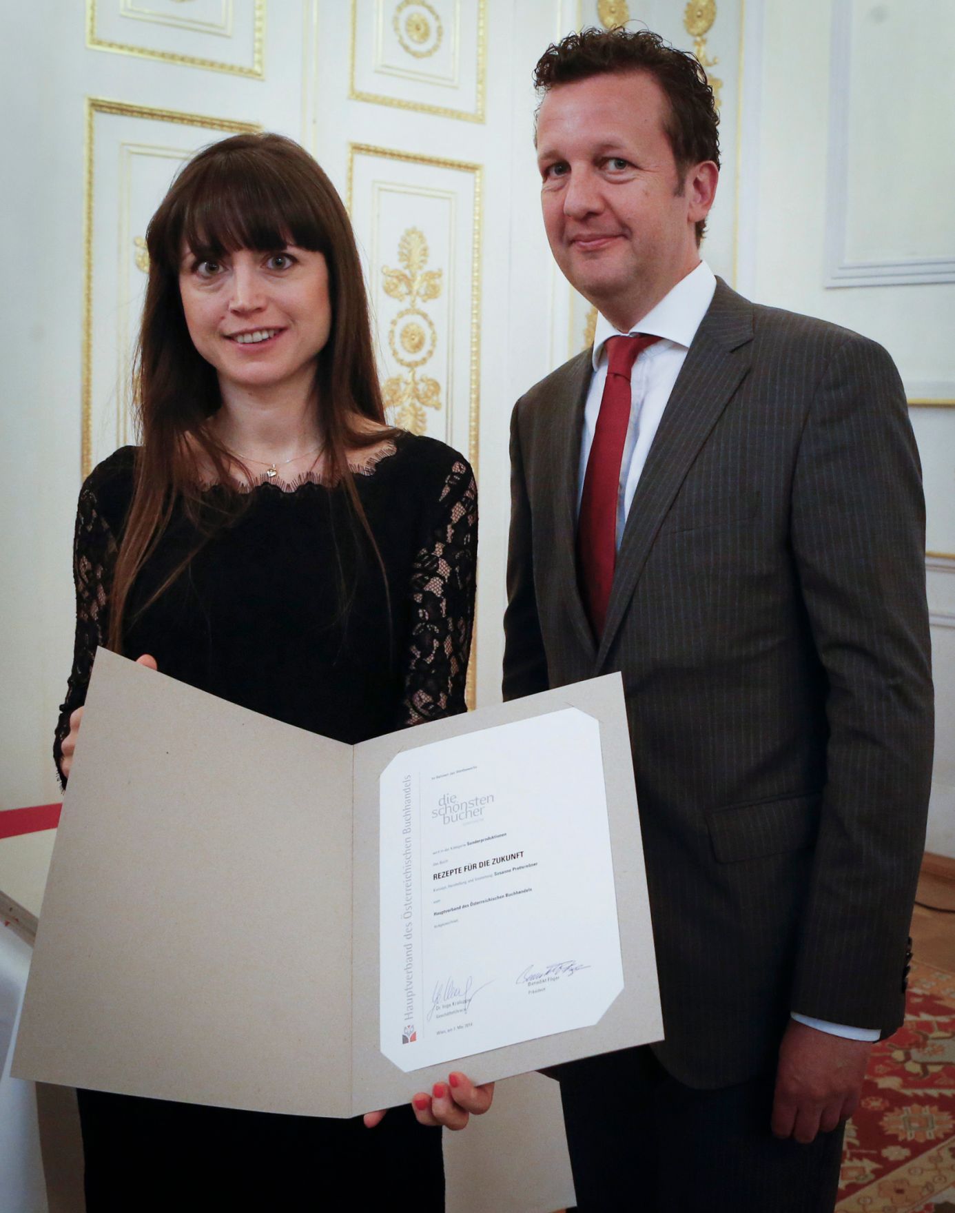 Am 7. Mai 2014 &uuml;berreichte der Pr&auml;sident des Hauptverbandes des &Ouml;sterreichischen Buchhandels Benedikt F&ouml;ger (r.) eine Ehrenurkunde an Susanne Pretterebner (l.) im Bundeskanzleramt.
