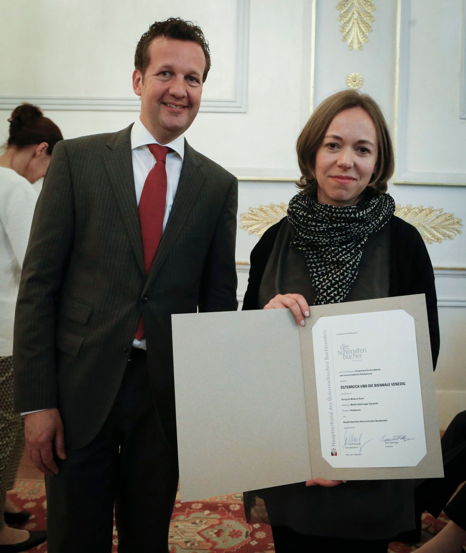 Am 7. Mai 2014 &uuml;berreichte der Pr&auml;sident des Hauptverbandes des &Ouml;sterreichischen Buchhandels Benedikt F&ouml;ger (l.) eine Ehrenurkunde an Martha Stutteregger (r.) im Bundeskanzleramt.