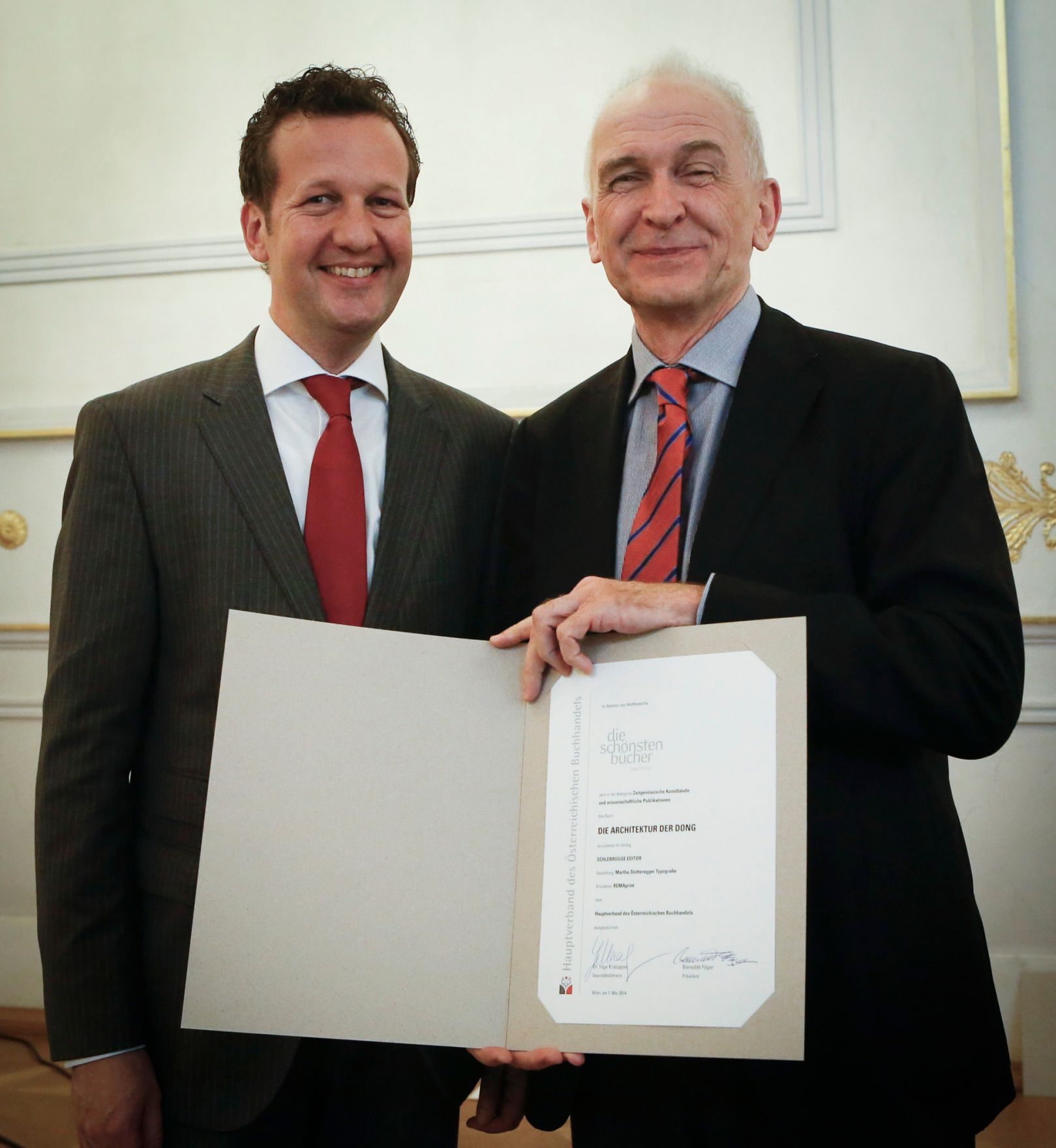 Am 7. Mai 2014 &uuml;berreichte der Pr&auml;sident des Hauptverbandes des &Ouml;sterreichischen Buchhandels Benedikt F&ouml;ger (l.) eine Ehrenurkunde an Johannes Schlebr&uuml;gge (r.) im Bundeskanzleramt.