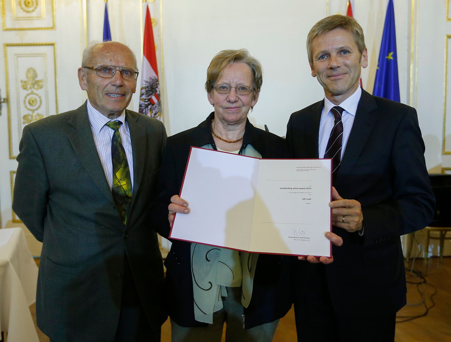 Am 10. September 2014 verlieh Kunst- und Kulturminister Josef Ostermayer (r.) die "outstanding artist awards 2014". Stellvertretend f&uuml;r die Preistr&auml;gerin Ulli Lust, Gewinnerin der Kategorie Karikatur und Comics, nahmen ihre Eltern die Auszeichnung entgegen.