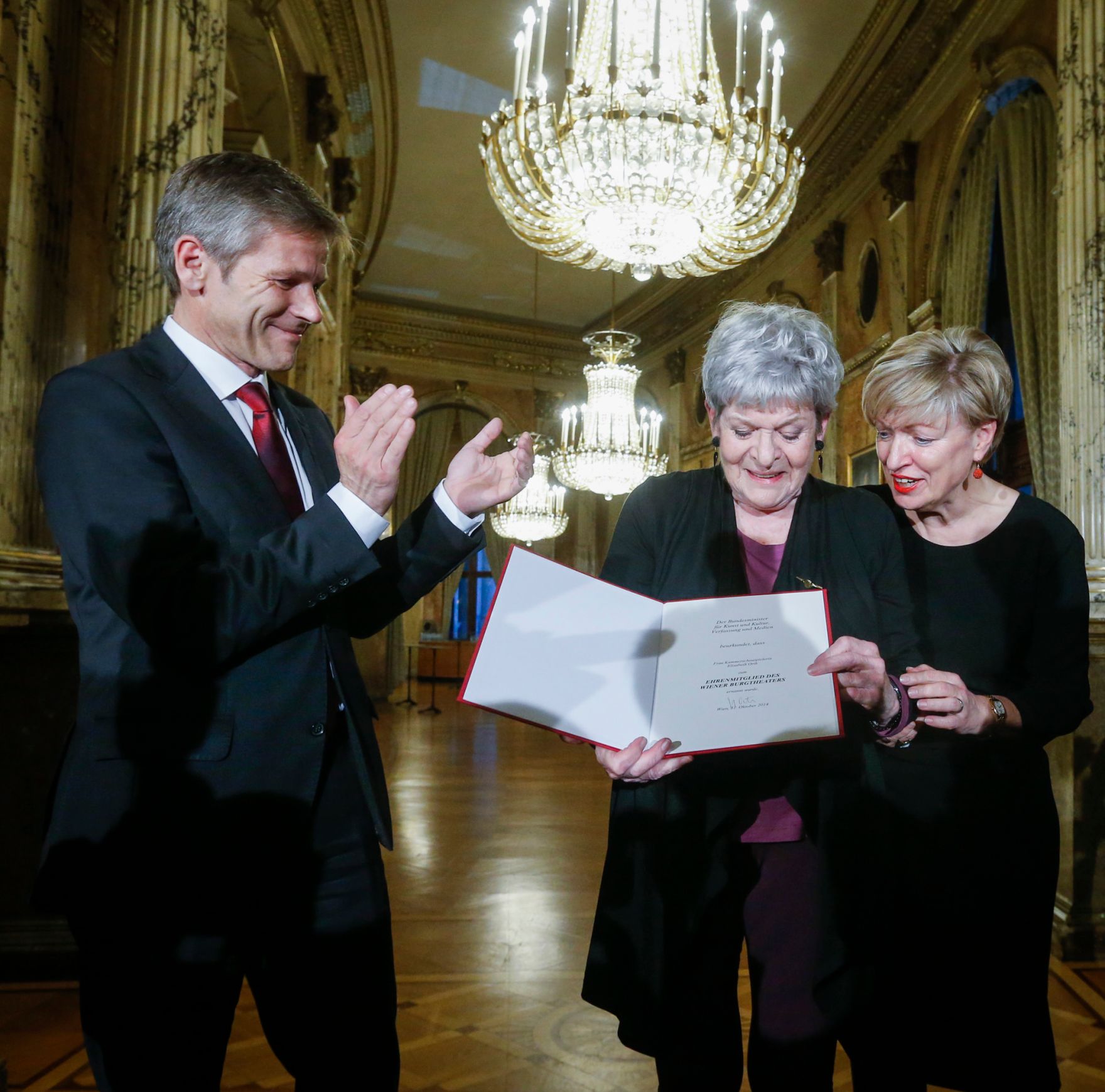 Anl&auml;sslich der Verleihung der Ehrenmitgliedschaft des Burgtheaters an Kammerschauspielerin Elisabeth Orth (m.), fand am 31. Oktober 2014 im Wiener Burgtheater die feierliche &Uuml;berreichung der Urkunde und des Ehrenringes durch Kunst- und Kulturminister Josef Ostermayer (l.) statt. Im Bild mit Burgtheaterdirektorin Karin Bergmann.