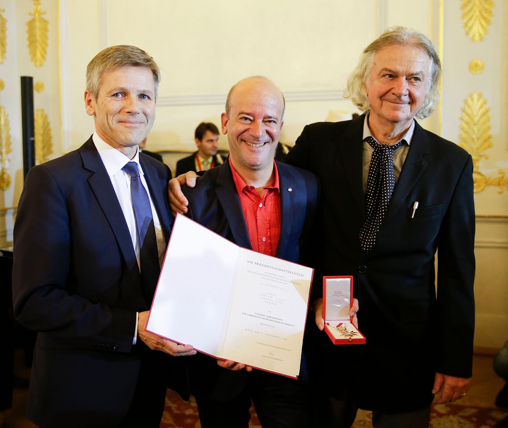 Am 3. November 2015 &uuml;berreichte Kunst- und Kulturminister Josef Ostermayer (l.) das Goldene Ehrenzeichen f&uuml;r Verdienste um die Republik &Ouml;sterreich an Andy Lee Lang (m.). Im Bild mit Peter Hofbauer (r.).