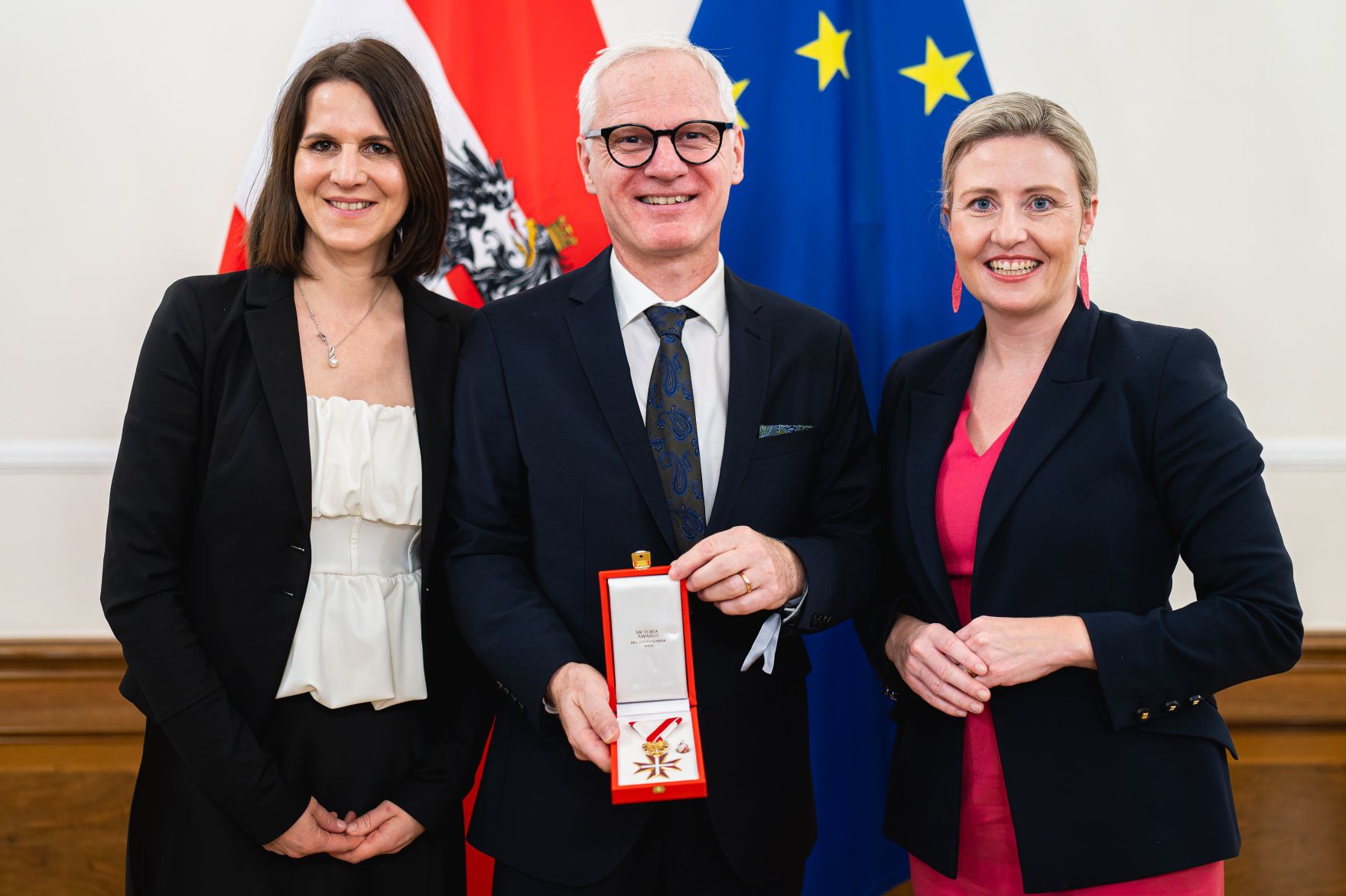 Am 12. November 2024 &uuml;berreichte Bundesministerin Susanne Raab (r.) Ehrenzeichen im Bundeskanzleramt. Im Bild mit Arno Melitopulos-Daum (m.).