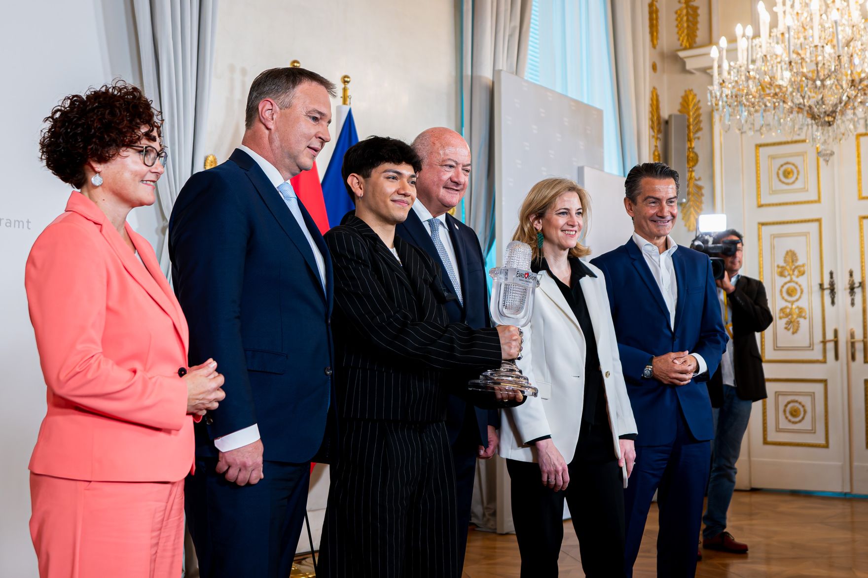 Am 19. Mai 2025 empfing Bundeskanzler Christian Stocker (4.v.l.) gemeinsam mit Vizekanzler Andreas Babler (2.v.l.), Bundesministerin Beate Meinl-Reisinger (5.v.l.) und Staatssekret&auml;rin Elisabeth Zehetner (l.) den Eurovision Song Contest-Sieger JJ (3.v.l.) im Bundeskanzleramt. Im Bild mit ORF Generaldirektor Roland Wei&szlig;mann (r.).