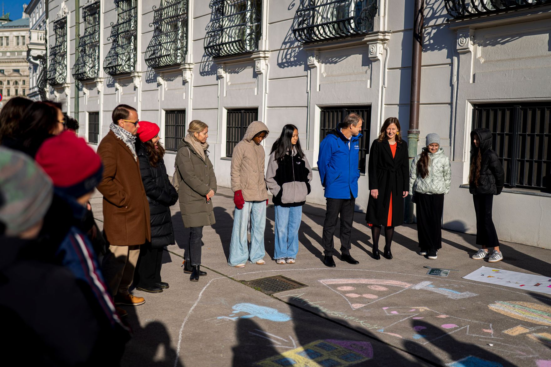 Am 19. November 2025 besuchte Bundesministerin Claudia Plakolm (3.v.r.) die Stra&szlig;enkreide-Malaktion zum Tag der Kinderrechte vor dem Bundeskanzleramt.