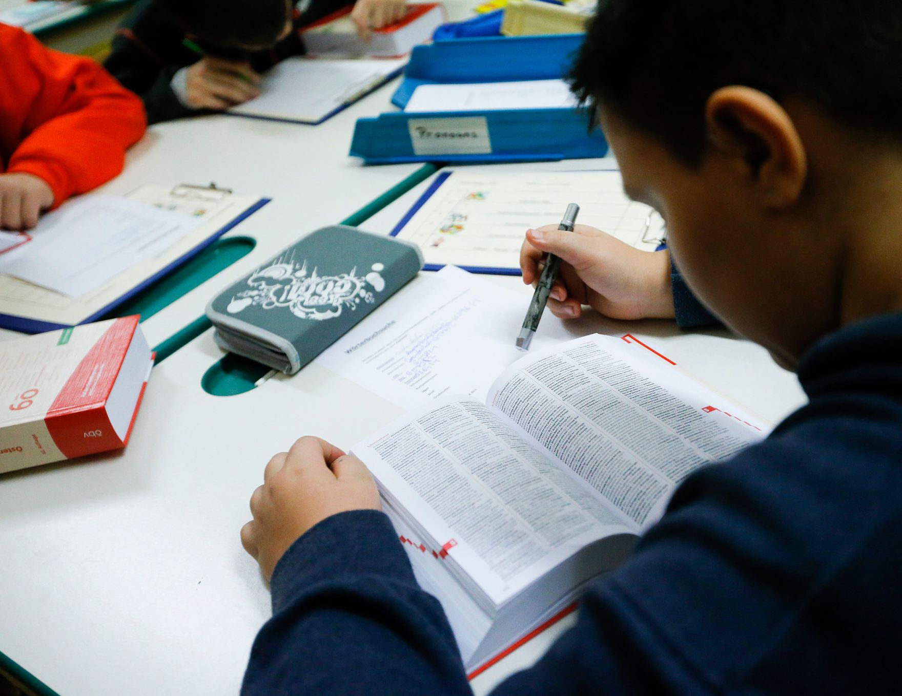 Sch&uuml;ler in einer Schule. Schlagworte: Bunt, Heft, Kind, lernen, lernen, Mensch, Stift, Tisch