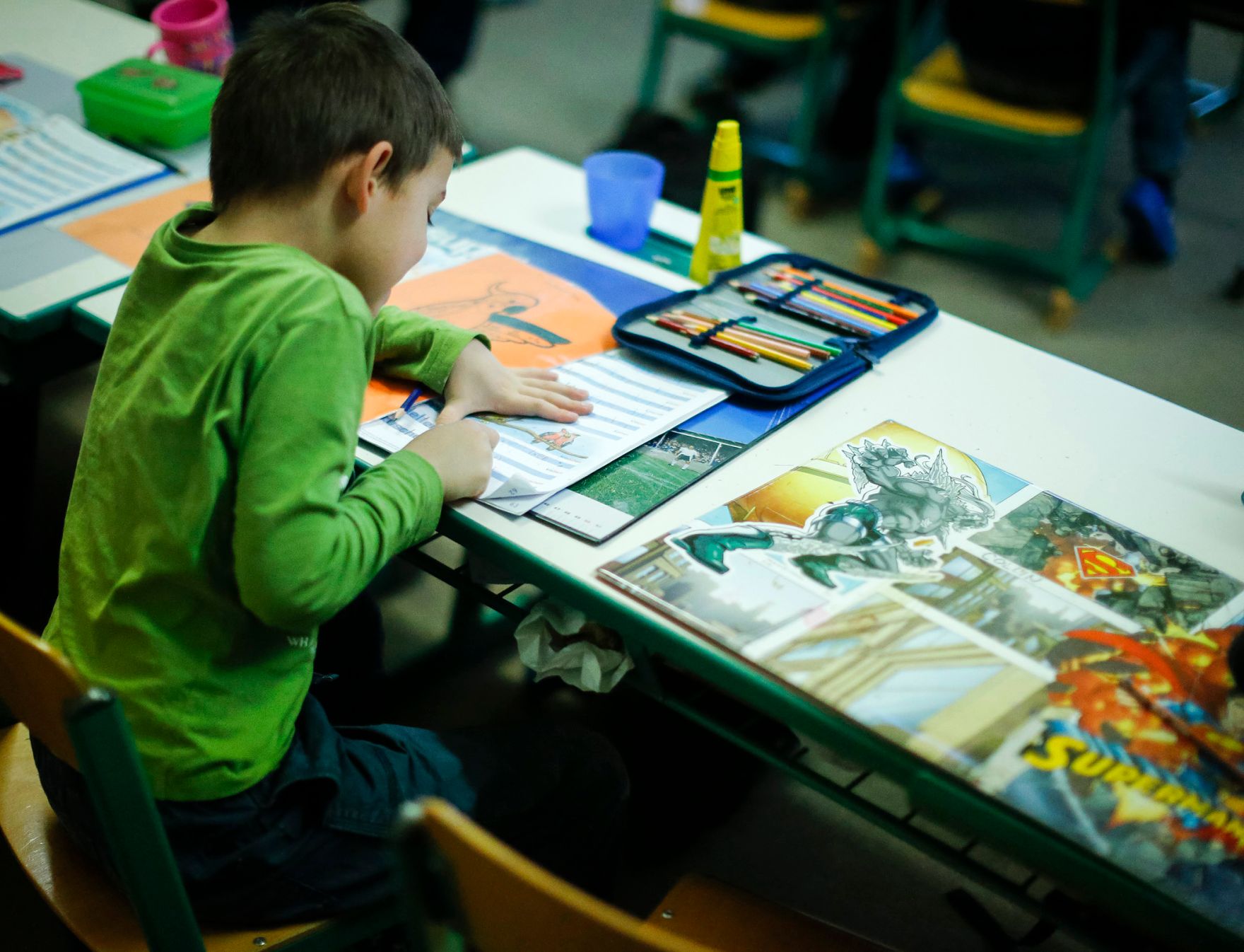 Sch&uuml;ler in einer Schule. Schlagworte: Bunt, Heft, Kind, lernen, Mensch, Stift, Tisch, Unterricht