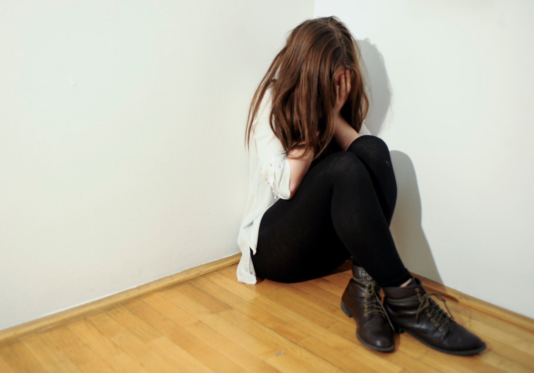 Eine &auml;ngstliche Frau kauert in einer Zimmerecke. Schlagworte: Angst, Frau, Gewalt, Menschen