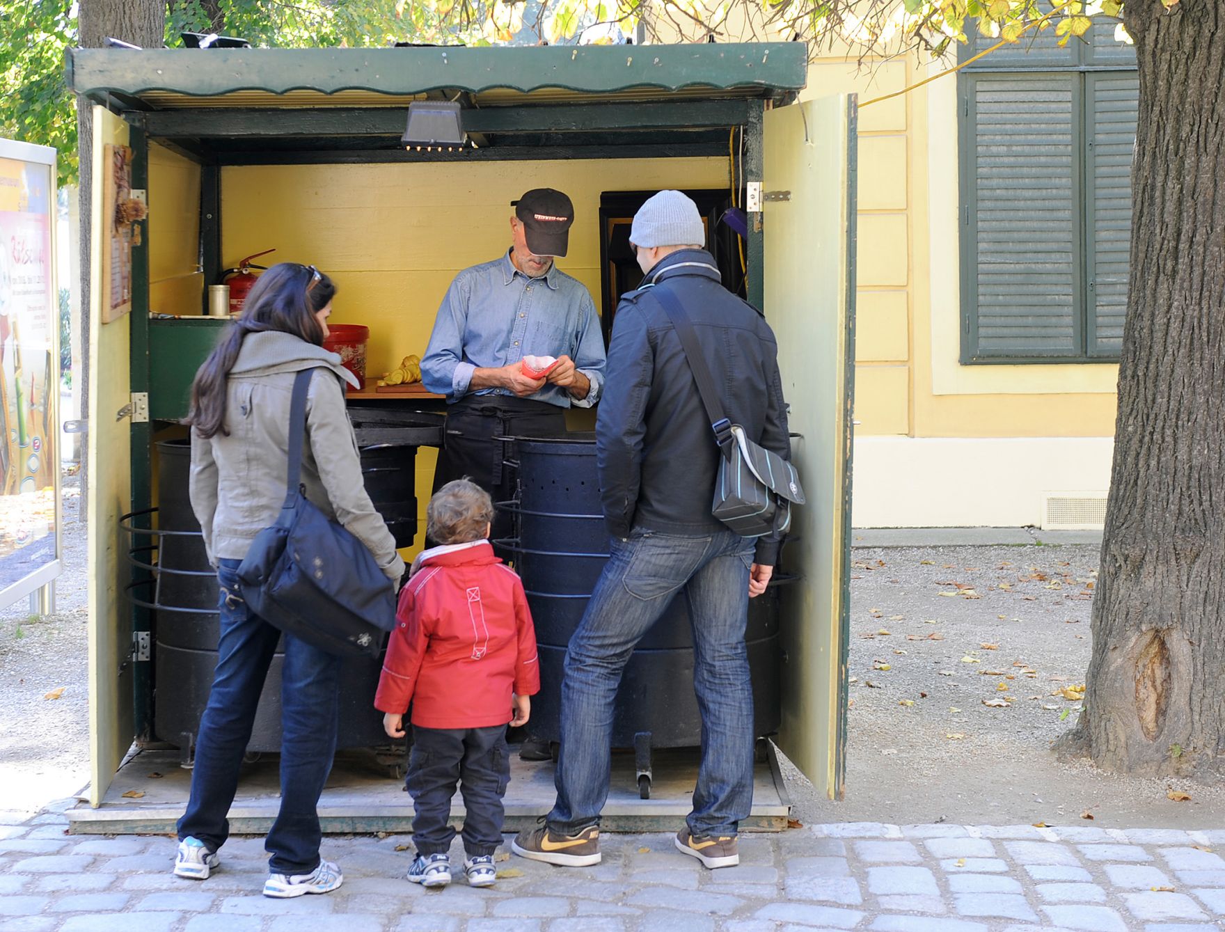 Im Bild ein Maronibrater mit Kunden. Schlagworte: Essen, Lebensmittel, Maroni, Maronistand, Menschen