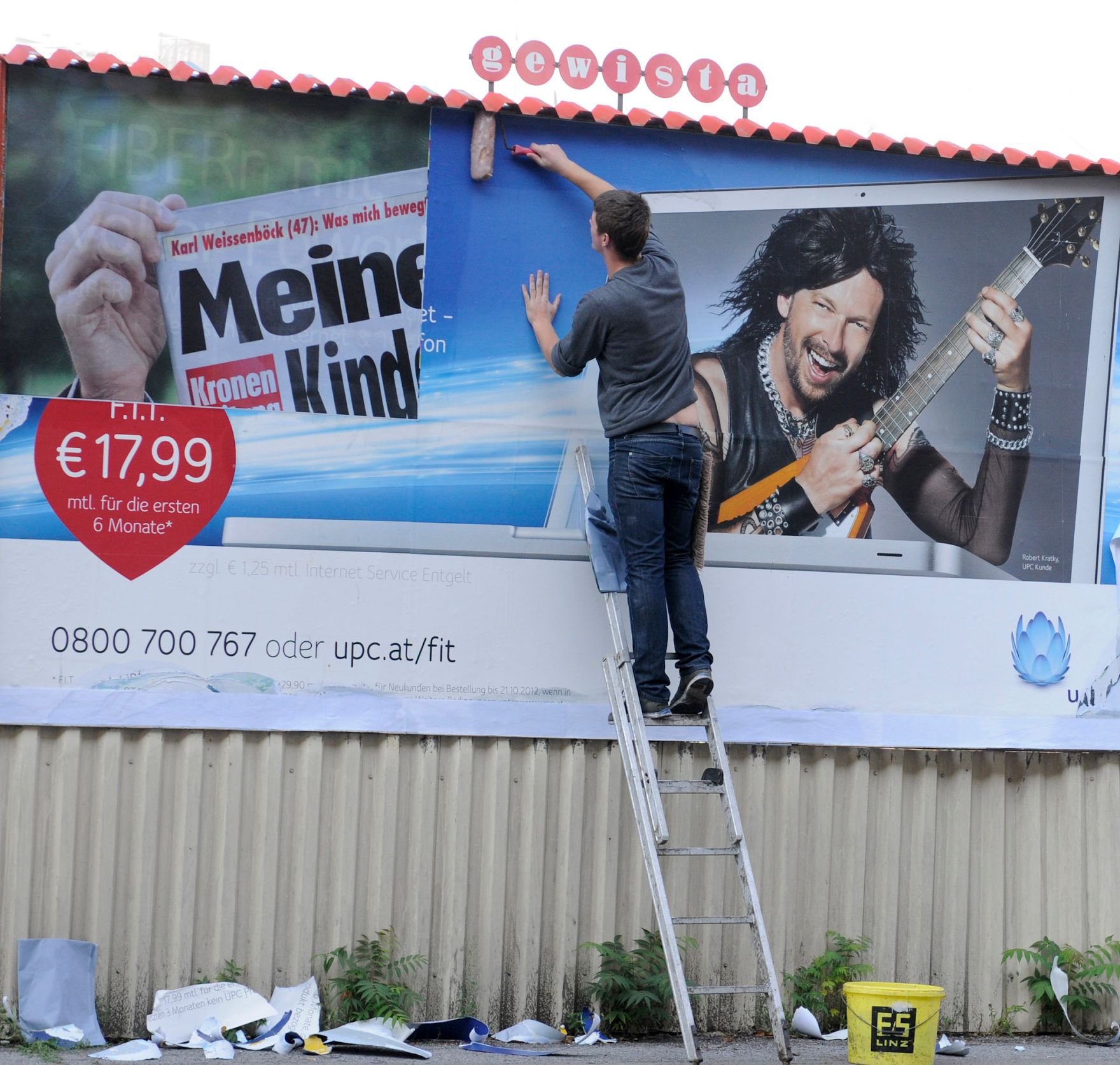 Ein Arbeiter beim Kleben eines neuen Werbeplakates. Schlagworte: Arbeit, Eimer, gewista, Leiter, Mann, Mensch, Plakatwand, Stadtleben, Werbung
