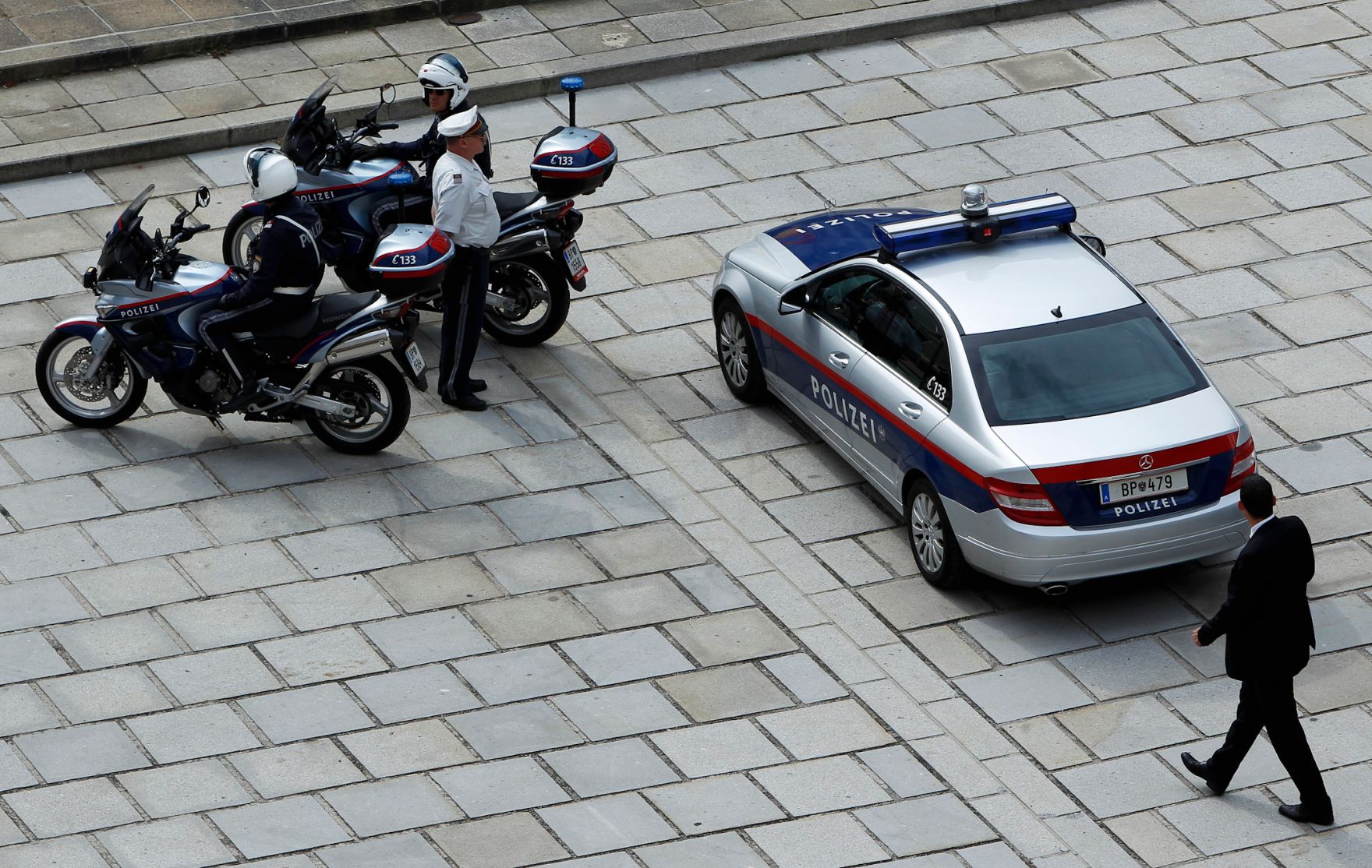 Polizisten mit Motorr&auml;dern und ein Einsatzfahrzeug. Schlagworte: Auto, Blaulicht, Eskorte, Fahrzeug, Mann, Mensch, Motorrad, Pflasterstein, PKW, Polizei, Sicherheit, Staatsbesuch, Sturzhelm, Uniform, Verkehr