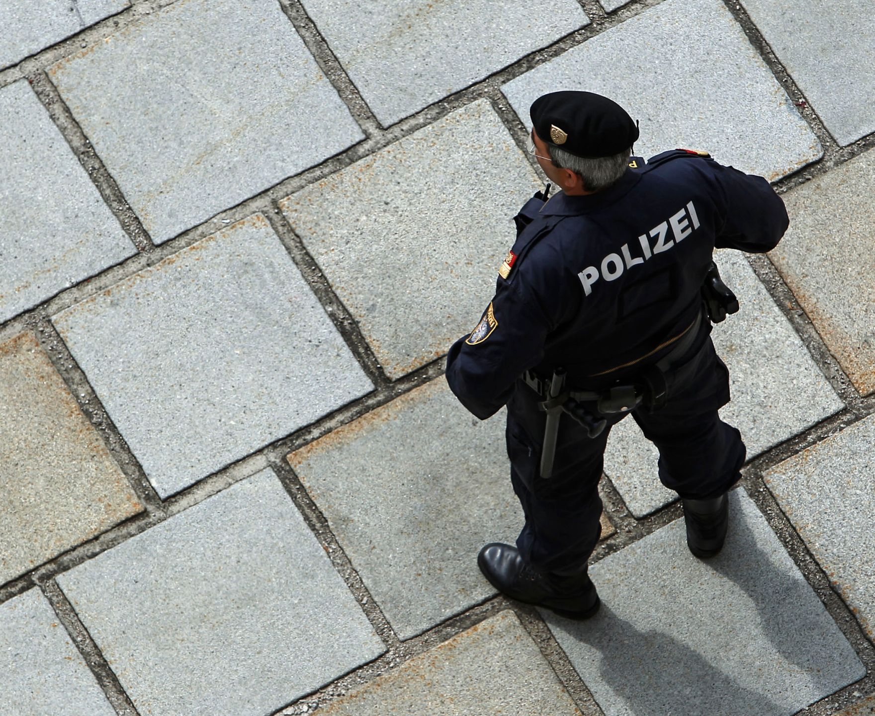 Ein Polizist, von oben gesehen. Schlagworte: Mann, Mensch, Pflasterstein, Polizei, Sicherheit, Uniform