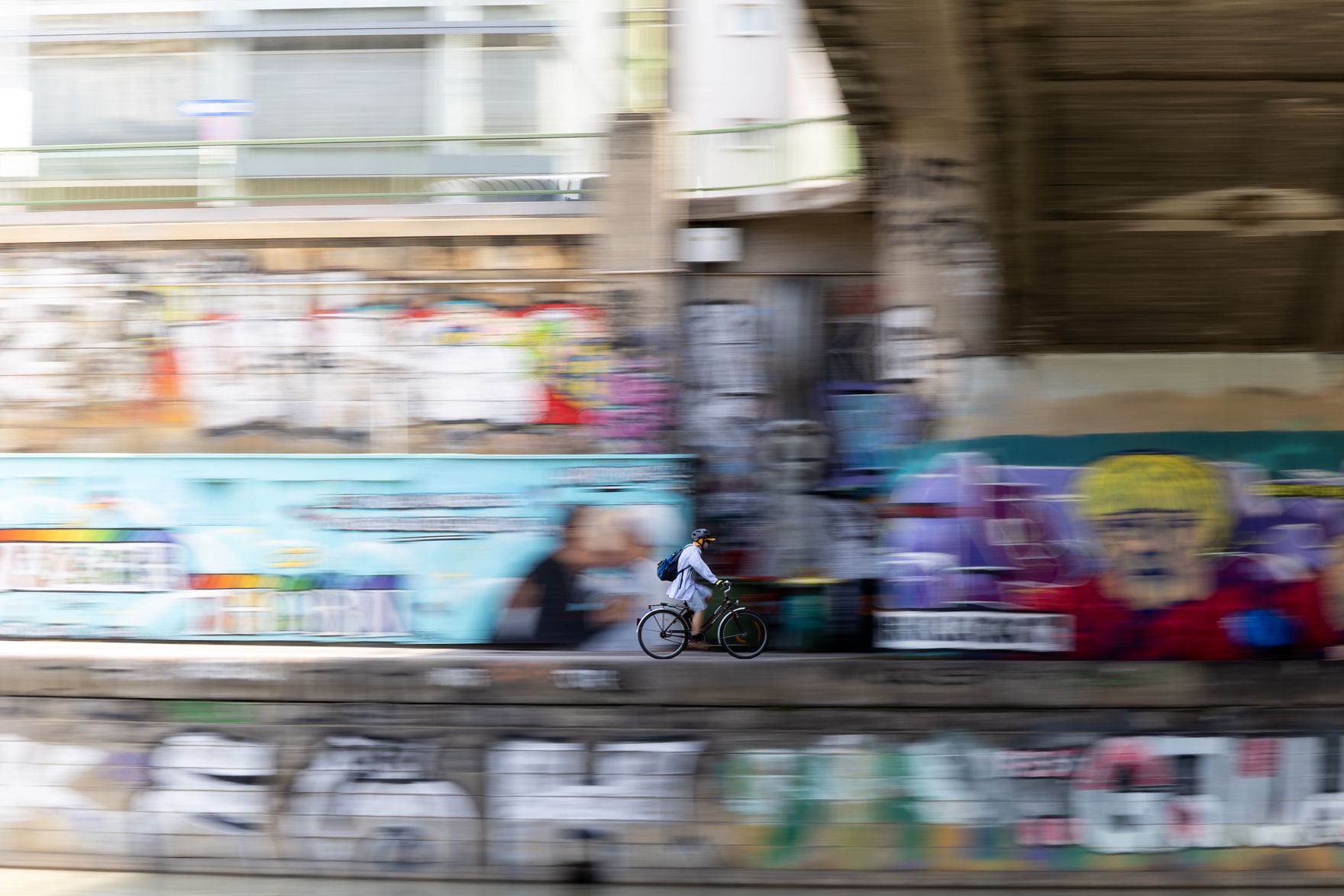 Eine Person f&auml;hrt Fahrrad am Donaukanal. Schlagw&ouml;rter: Fahrrad, Donaukanal, Graffiti