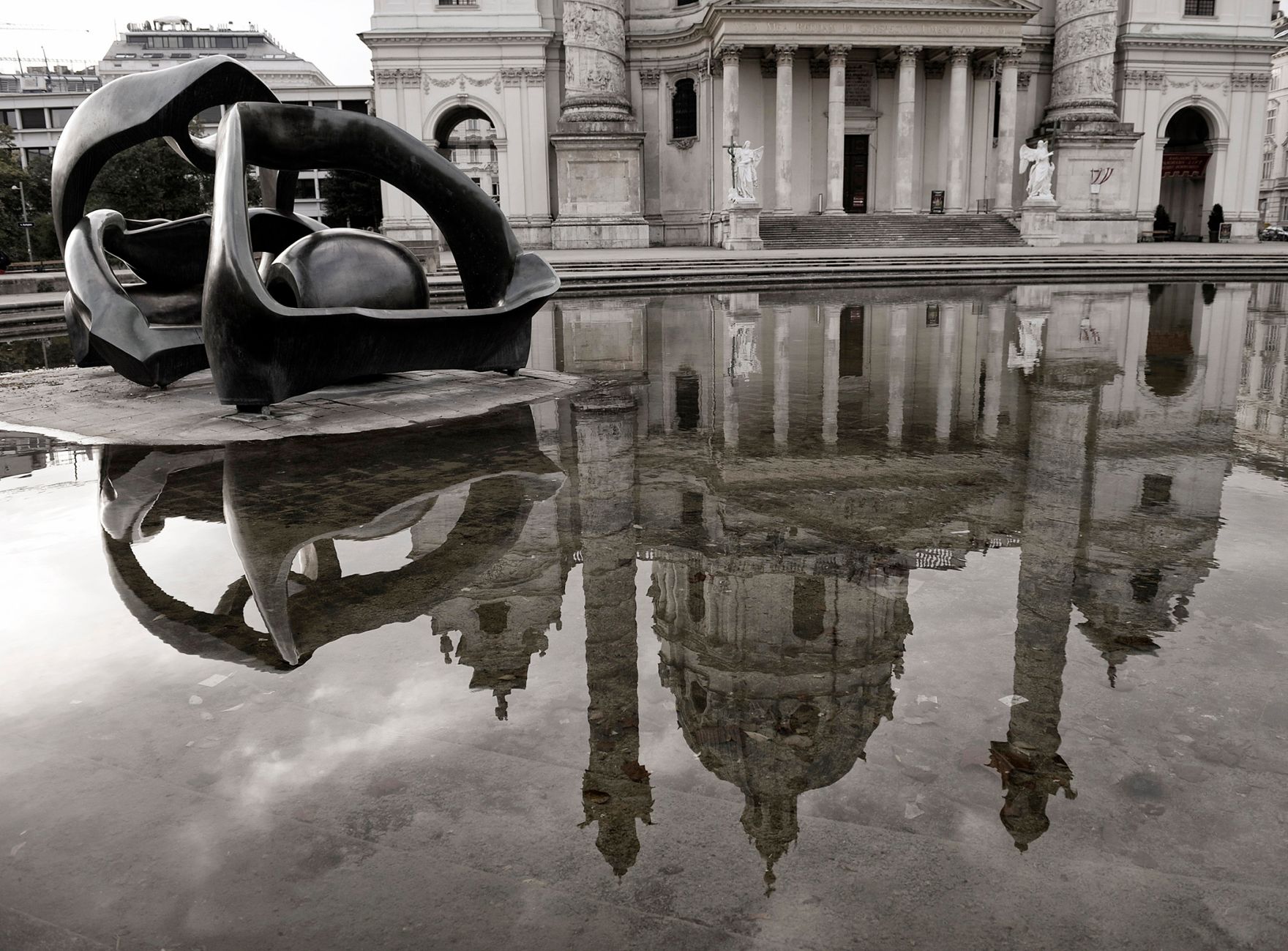 Spiegelung der Karlskirche und der Skulptur &quot;Hill Arches&quot; in dem Wasserbecken am Karlsplatz. Schlagworte: Geb&auml;ude, Karlskirche, Kirche, Stadtlandschaft, Sehensw&uuml;rdigkeit, Skulptur, Spiegelung, Wasser