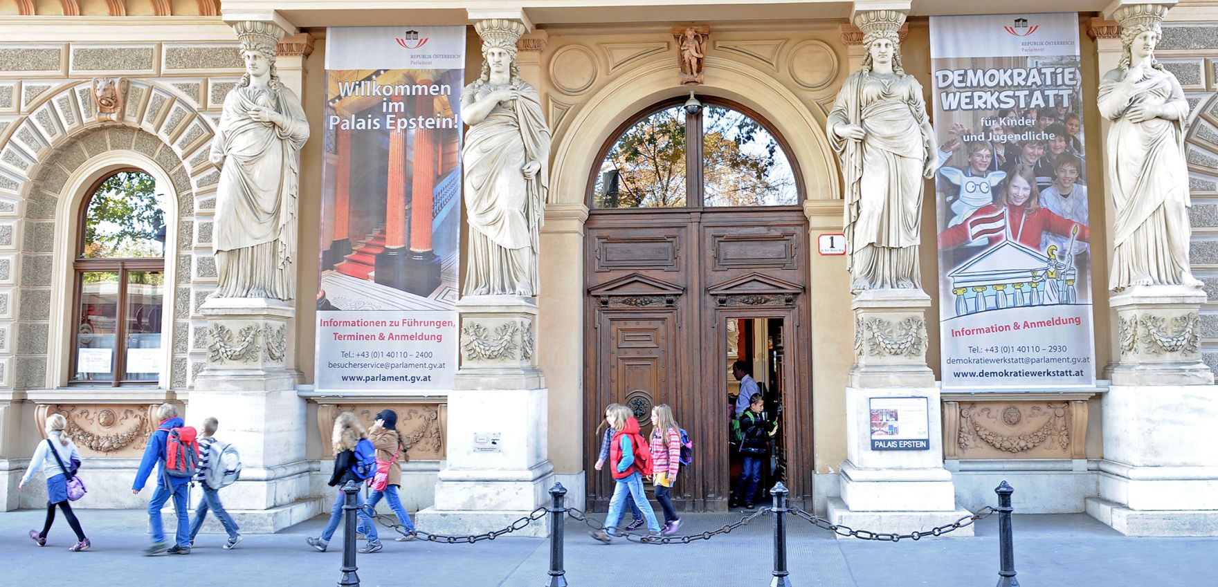 Schulkinder beim Verlassen des Palais Epstein. Schlagworte: Architektur, Geb&auml;ude, Personen, Statue, Sehensw&uuml;rdigkeit, Stadtlandschaft, Tor, T&uuml;r
