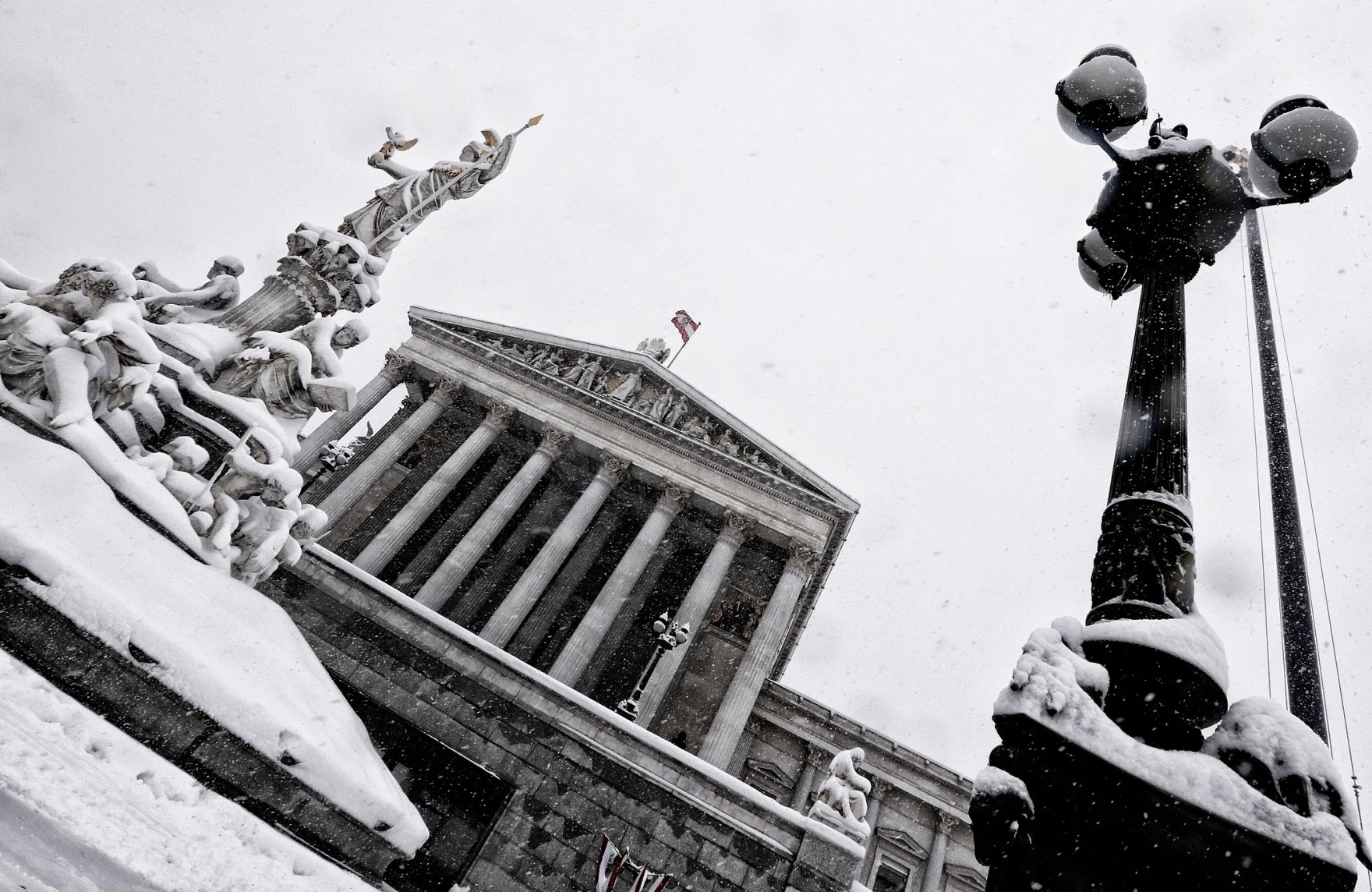 Eine winterliche Aufnahme des Parlamentsgeb&auml;udes mit dem Pallas Athene Brunnen davor. Schlagworte: Architektur, Brunnen, Denkmal, Geb&auml;ude, Schnee, Statue, Sehensw&uuml;rdigkeit, Stadtlandschaft, Winter