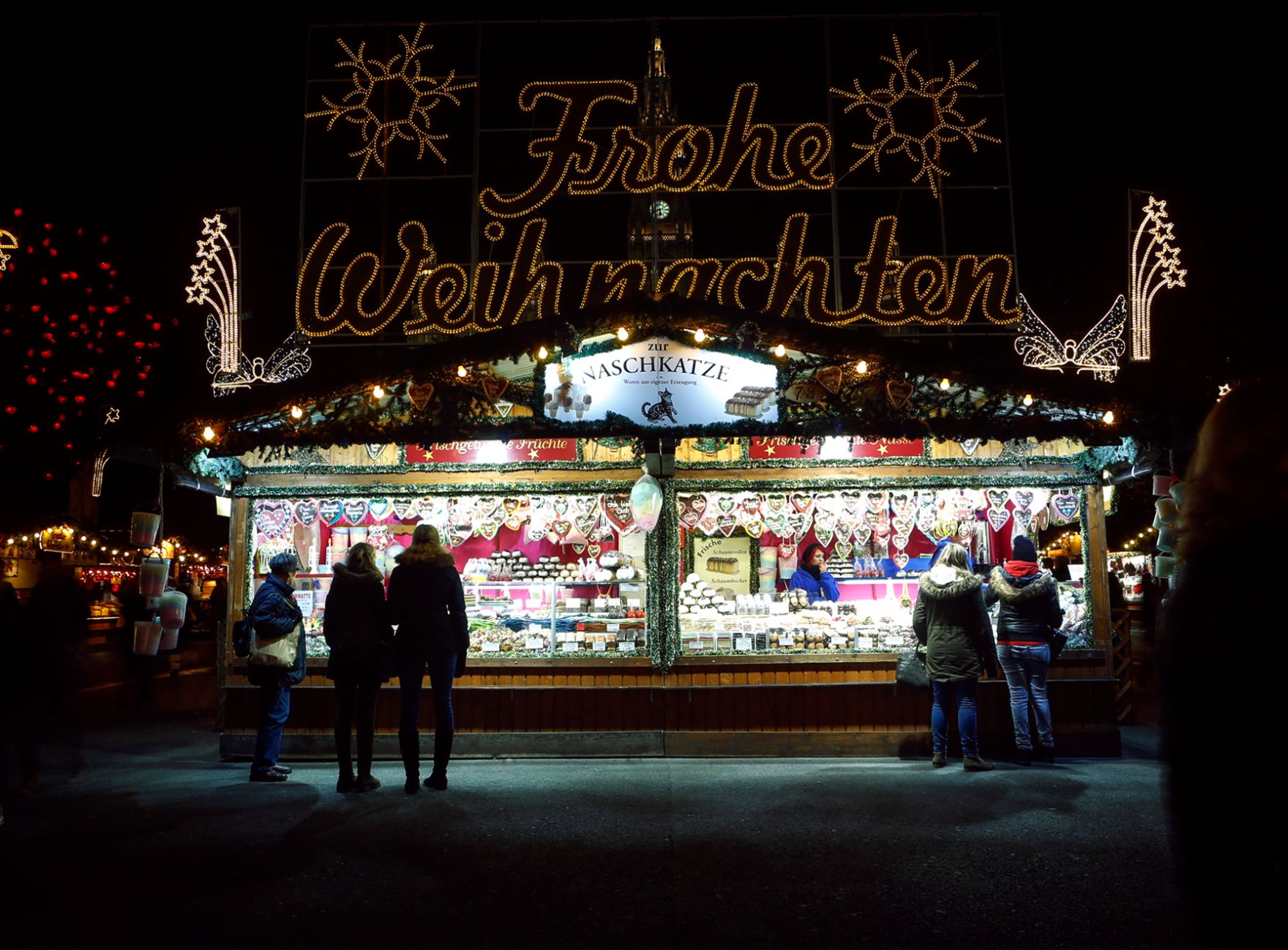 Der Christkindlmarkt am Rathausplatz bei Nacht. Schlagworte: Abend, Beleuchtung, Kugeln, Marktstand, Menschen, Sehensw&uuml;rdigkeit, Stadtlandschaften, Weihnachten