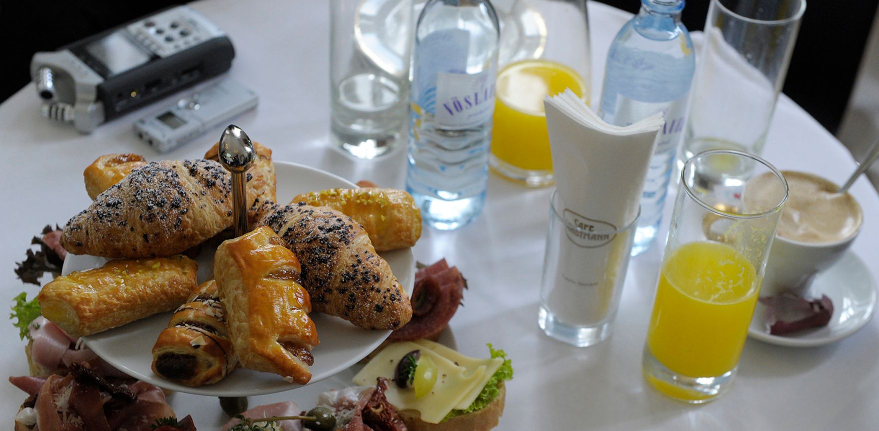 Pressefr&uuml;hst&uuml;ck im Wiener Cafe Landtmann. Schlagworte: Aufnahmeger&auml;t, Br&ouml;tchen, Cafe, Essen, Fr&uuml;hst&uuml;ck, Gl&auml;ser, Kaffee, Kipferl, Orangensaft, Plundergeb&auml;ck, Tasse, Tisch, Tischtuch