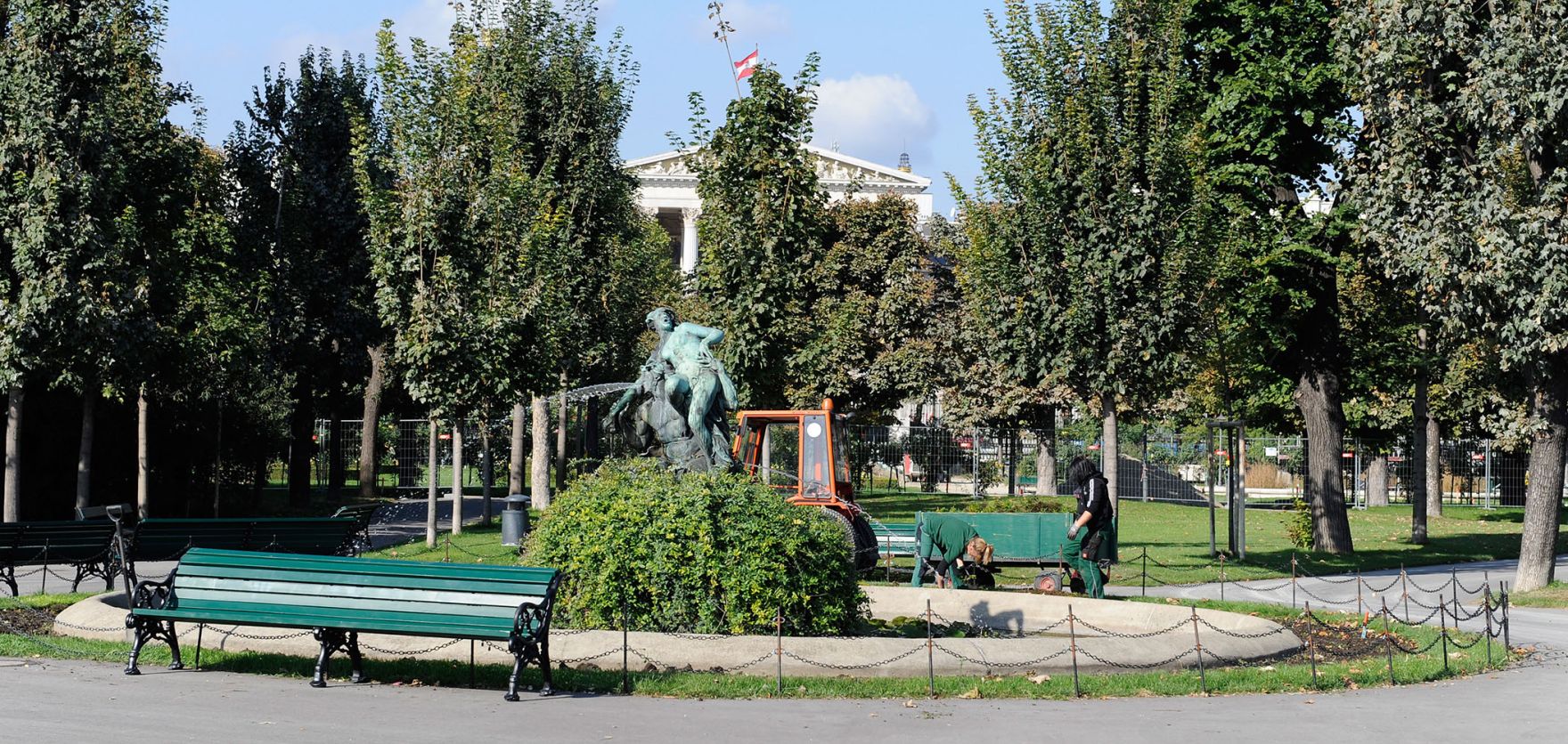 Bei dem Triton- und Nymphenbrunnen im Volksgarten werden Gartenarbeiten durchgef&uuml;hrt. Schlagworte: Brunnen, B&auml;ume, Menschen, Natur, Park, Parkbank, Pflanzen, Stadtlandschaft, Wasser