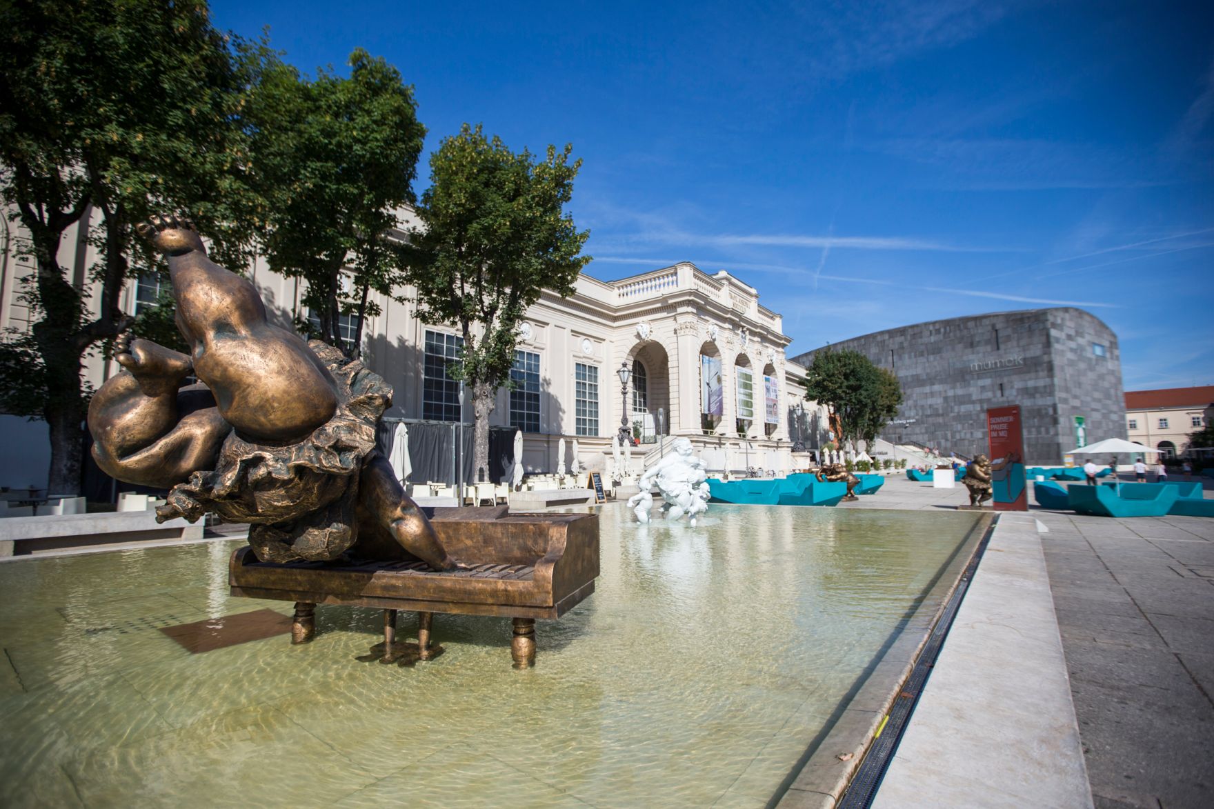Skulpturen des chinesischen K&uuml;nstlers Xu Hongfei aus der Chubby Women Sammlung im Haupthof des Museumsquartiers. Schlagworte: Ausstellung, Architektur, Brunnen, Frau, Geb&auml;ude, Klavier, Kunst, K&uuml;nstler, MQ, Museum, Sehensw&uuml;rdigkeit, Skulptur, Stadtlandschaft, Wasser