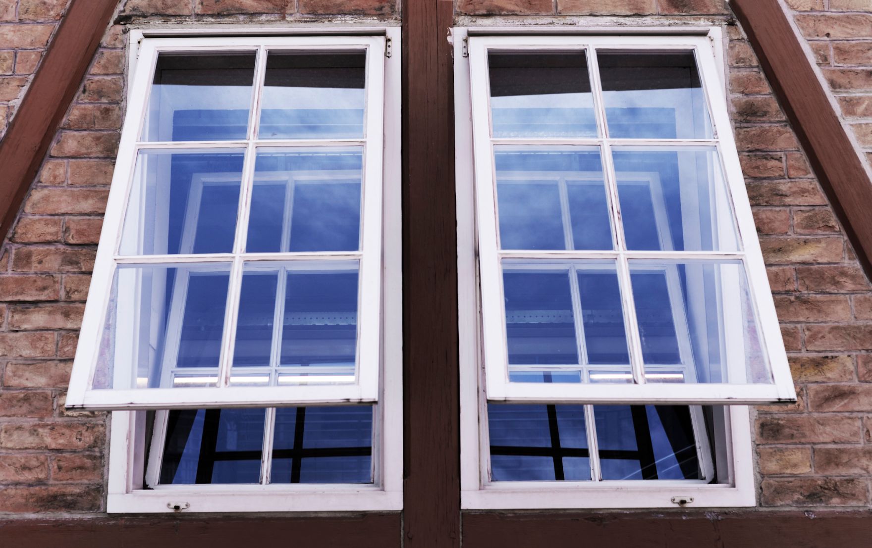 Eine Ziegelsteinfassade mit zwei gekippten Fenstern. Schlagworte: Geb&auml;ude, Stadtlandschaft