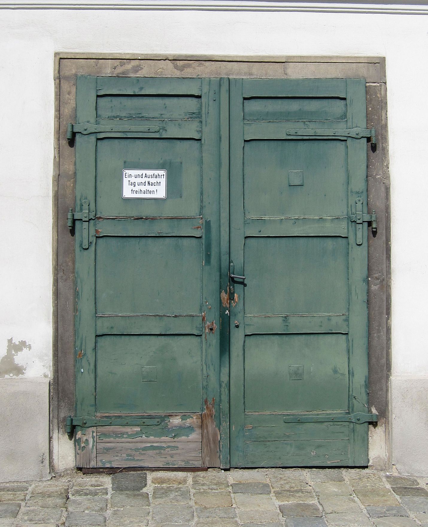 Altes, gr&uuml;nes Tor mit einem Schild "Ein- und Ausfahrt Tag und Nacht freihalten!" am Heiligenkreuzerhof. Schlagworte: Geb&auml;ude, Schild, Stadtlandschaft, Tor, T&uuml;r