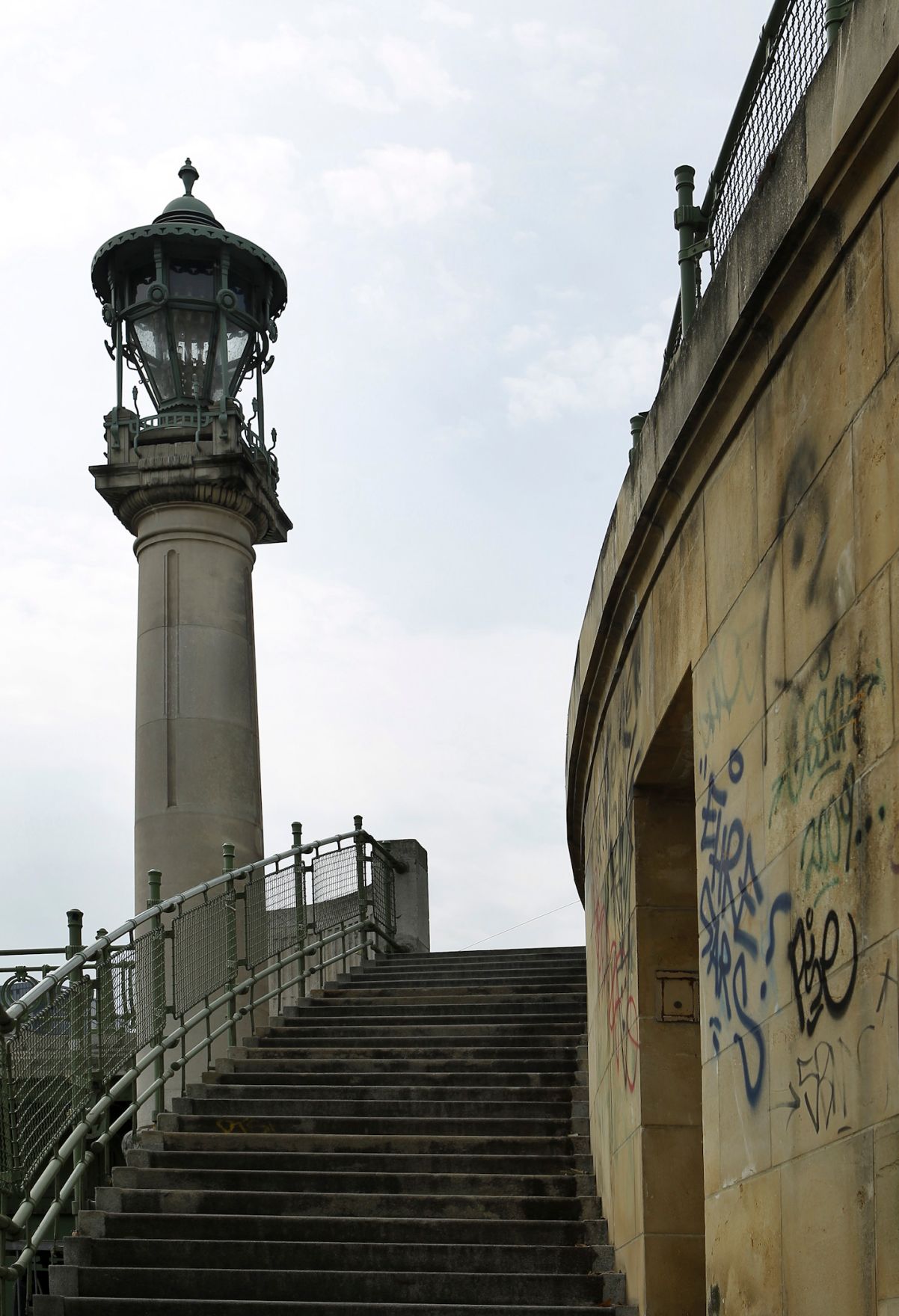 Eine alte Laterne bei einem Stiegenabgang zum Donaukanal. Schlagworte: Abgang, Aufgang, Gel&auml;nder, Graffiti, Laterne, Stadtlandschaft, Stufen, Treppe