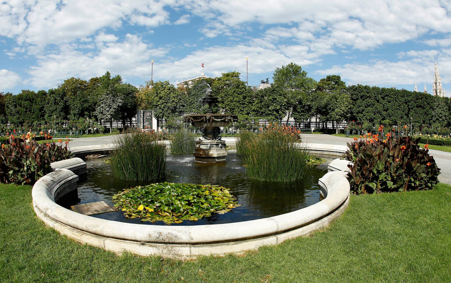 Ein Springbrunnen im Volksgarten. Schlagworte: Brunnen, B&auml;ume, Himmel, Natur, Park, Pflanzen, Stadtlandschaft, Wasser, Wiese, Wolken