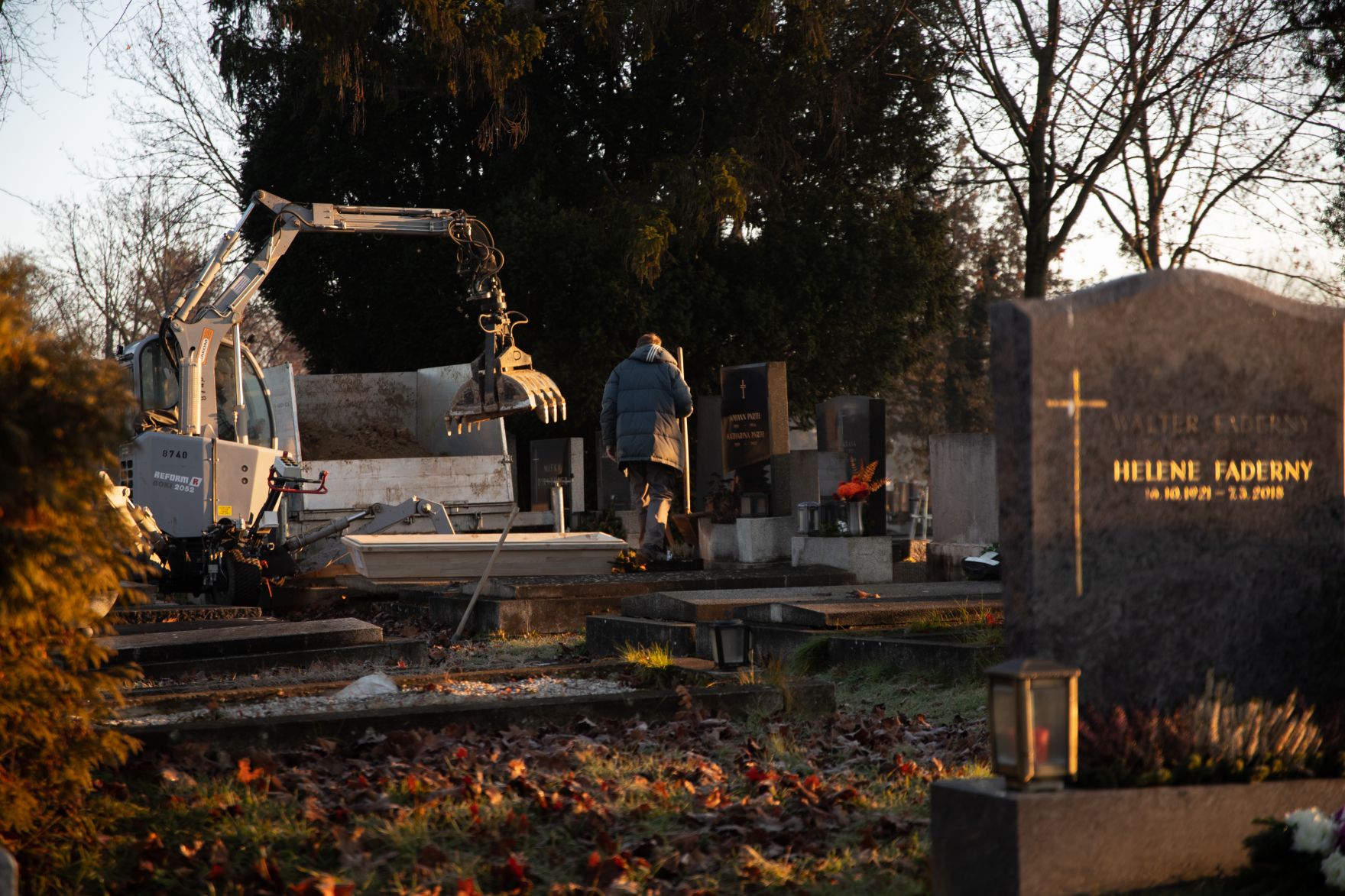 Zentralfriedhof von Wien Schlagw&ouml;rter: Zentralfriedhof, Bagger, Kreuz, Grabsteine, Menschen, Laub, Fr&uuml;hling, Winter, Schaufel, Wien, Baum, B&auml;ume, Jacke, Braun, Gr&uuml;n, Dunkelblau, Hellgr&uuml;n, Kerze, Kerzen, Tod, Gr&auml;ber, Stille, Ruhe, Lichter
