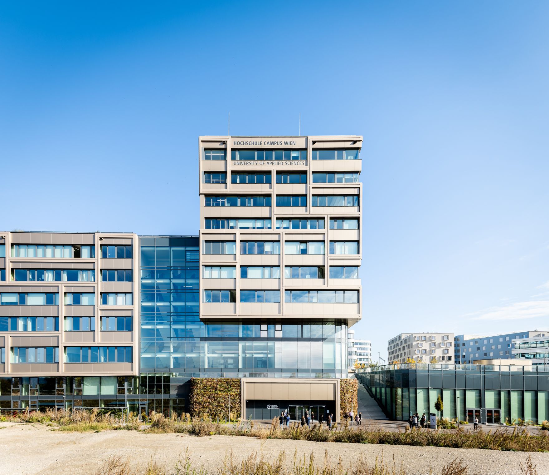 Hochschule Campus Wien au&szlig;en &ndash; Moderner Hochschulkomplex mit Glasfassade und weitl&auml;ufigem Vorplatz Hochschule Campus Wien, Fachhochschule Wien, Hochschule, Studium, Bildung, Forschung, Wissenschaft, Universit&auml;tsgeb&auml;ude, moderner Campus, Architektur, Glasfassade, Neubau, Bildungseinrichtung, Favoriten, 10. Bezirk Wien, Stadtentwicklung, Lifesciences, Technik, Gesundheitswesen, Soziales, modernes Wien, urbaner Raum, nachhaltige Architektur, Bildungscampus