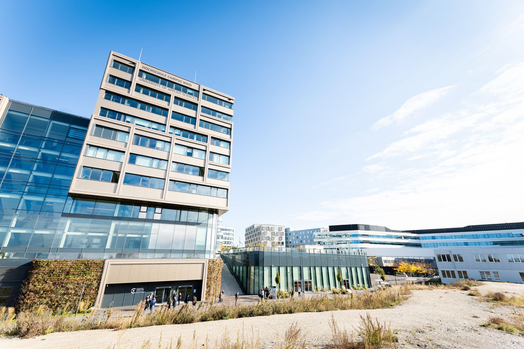Hochschule Campus Wien au&szlig;en &ndash; Moderner Hochschulkomplex mit Glasfassade und weitl&auml;ufigem Vorplatz Hochschule Campus Wien, Fachhochschule Wien, Hochschule, Studium, Bildung, Forschung, Wissenschaft, Universit&auml;tsgeb&auml;ude, moderner Campus, Architektur, Glasfassade, Neubau, Bildungseinrichtung, Favoriten, 10. Bezirk Wien, Stadtentwicklung, Lifesciences, Technik, Gesundheitswesen, Soziales, modernes Wien, urbaner Raum, nachhaltige Architektur, Bildungscampus
