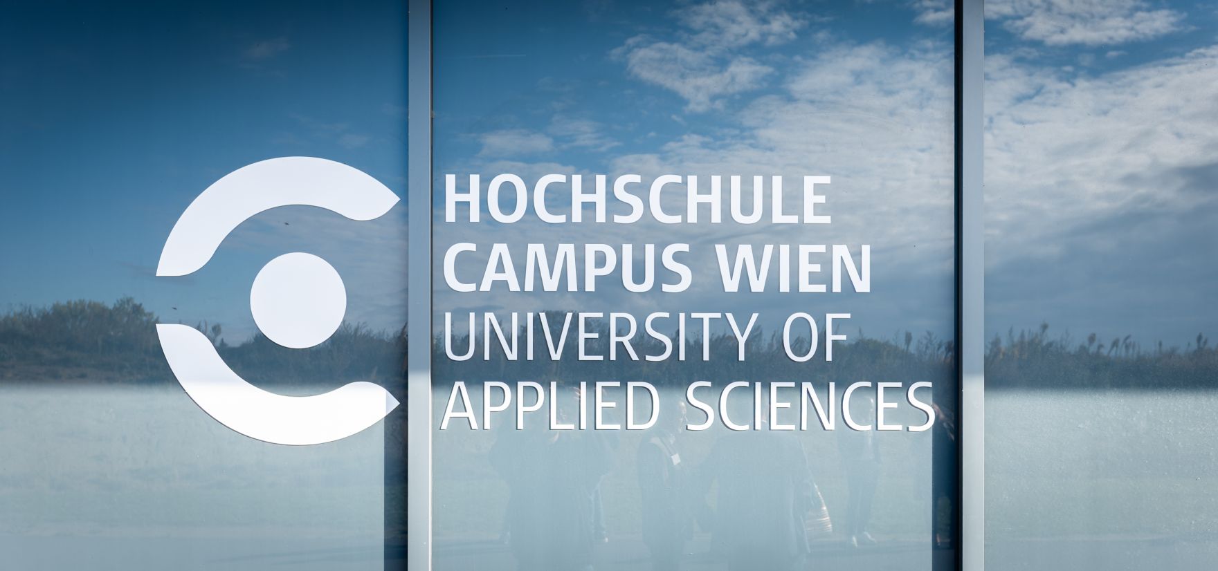 Hochschule Campus Wien au&szlig;en &ndash; Moderner Hochschulkomplex mit Glasfassade und weitl&auml;ufigem Vorplatz Hochschule Campus Wien, Fachhochschule Wien, Hochschule, Studium, Bildung, Forschung, Wissenschaft, Universit&auml;tsgeb&auml;ude, moderner Campus, Architektur, Glasfassade, Neubau, Bildungseinrichtung, Favoriten, 10. Bezirk Wien, Stadtentwicklung, Lifesciences, Technik, Gesundheitswesen, Soziales, modernes Wien, urbaner Raum, nachhaltige Architektur, Bildungscampus