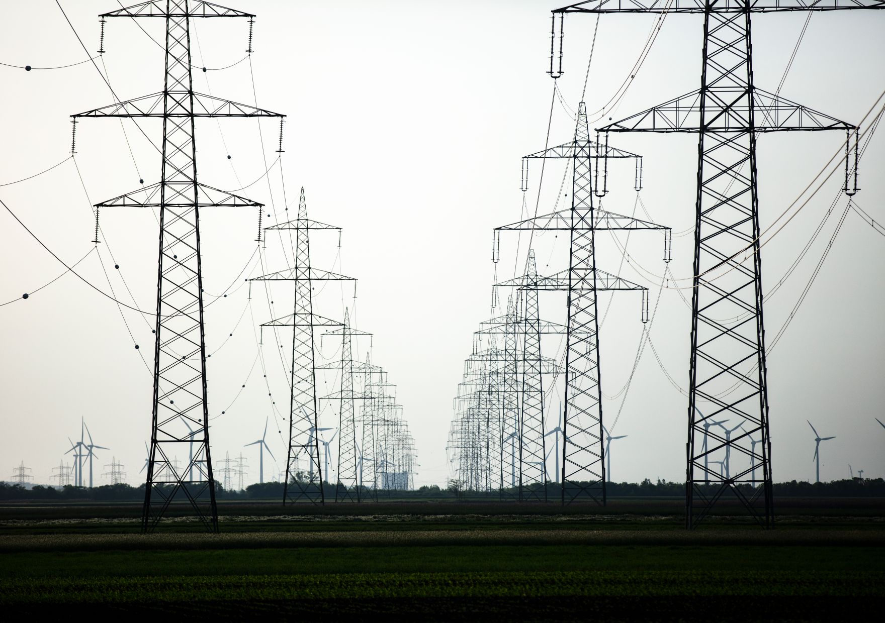 Windkraftanlagen in Betrieb, umgeben von Hochspannungsleitungen. Schlagw&ouml;rter: Windkraftanlagen, Wind, Energie, Technik, Strom, Nachhaltigkeit, Hochspannung, Rat f&uuml;r Verkehr, Telekommunikation und Energie, TTE