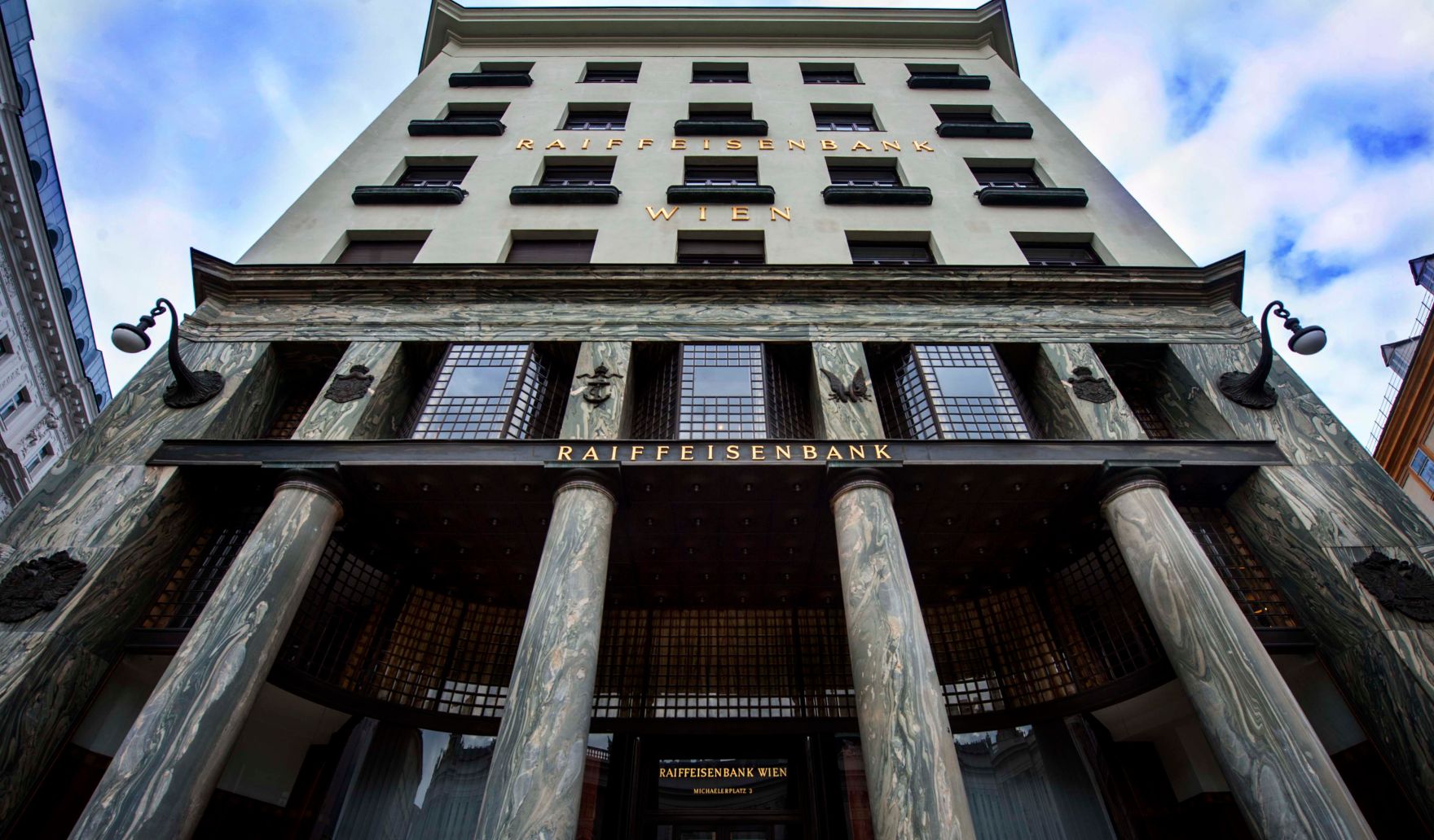 Eine Raiffeisenbank am Michaelaplatz. Schlagworte: Fenster, Geb&auml;ude, S&auml;ulen, Stadtlandschaft, Wirtschaft, Wolken