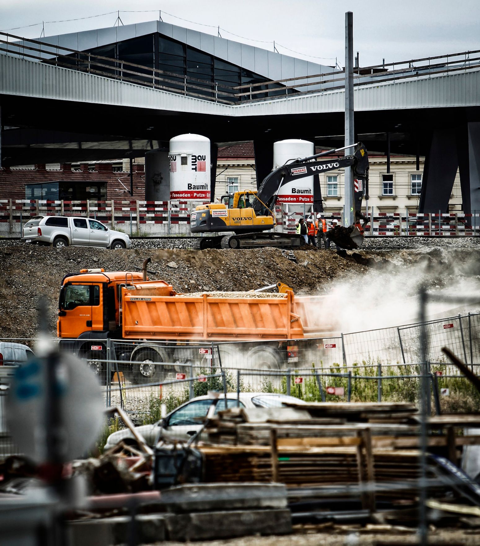 Fahrzeuge auf der Baustelle des &Ouml;BB Hauptbahnhofes in Wien. Schlagworte: Arbeiter, Auto, Bagger, Baustelle, Fahrzeug, LKW, Menschen, PKW, Staub, Wirtschaft