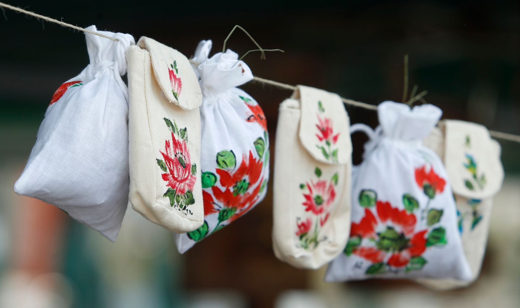 Mit Blumenmotiven bedruckte Stoffs&auml;ckchen h&auml;ngen auf einer Leine. Schlagworte: Bauernmarkt, Handarbeit, Leine, Leinen, Markt, Wirtschaft