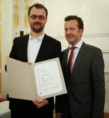 Am 7. Mai 2014 &uuml;berreichte der Pr&auml;sident des Hauptverbandes des &Ouml;sterreichischen Buchhandels Benedikt F&ouml;ger (r.) eine Ehrenurkunde an Axel K&ouml;hne (l.) im Bundeskanzleramt.