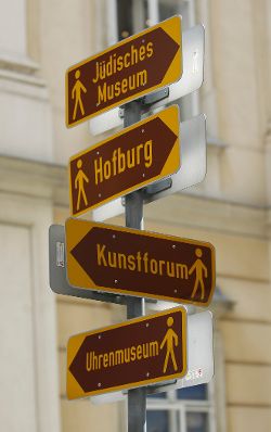 Hinweisschilder in der Wiener Innnenstadt: J&uuml;disches Museum, Hofburg, Kunstforum, Uhrenmuseum Schlagworte: Beschriftung, Pfeile, Schild, Wegweiser