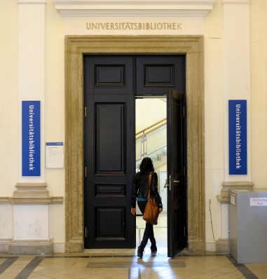 Aufnahme an der Hauptuniversit&auml;t Wien. Eine Studentin beim Besuch der Universit&auml;tsbibliothek. Schlagworte: Bibliothek, Bildung, Frau, Handtasche, Studentin, Tor, T&uuml;r, Menschen, Universit&auml;t