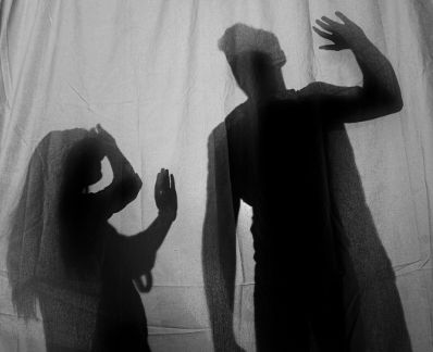 Ein Mann bedroht eine Frau mit erhobener Hand. Schlagworte: Abwehr, Angst, Faust, Frau, Gewalt, Hand, Mann, Menschen, Schatten, schlagen