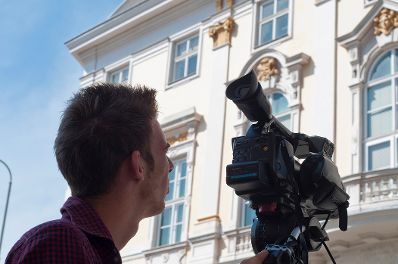 Ein Kameramann bei der Arbeit vor dem Bundeskanzleramt. Schlagworte: Ballhausplatz, Fenster, Film, Geb&auml;ude, Kunst, Mann, Mensch, Presse, Stadtleben, Videokamera